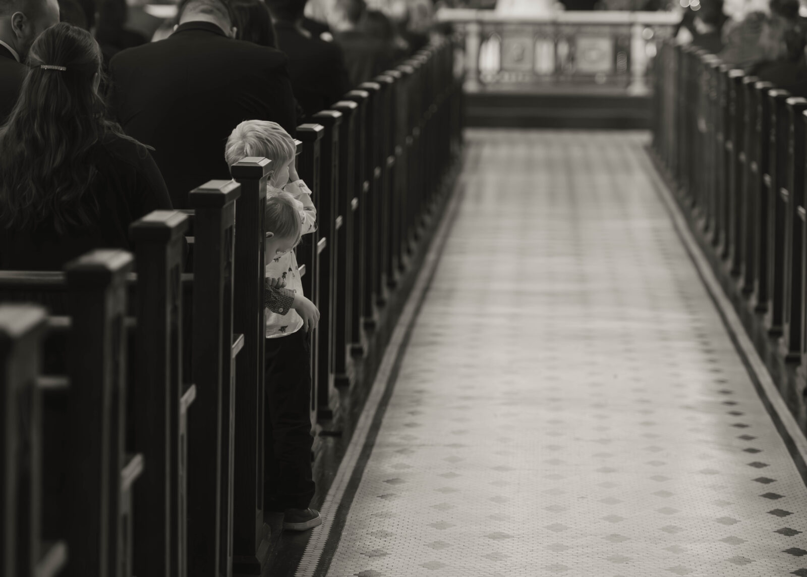 Two children peek down the main aisle during a Nuptial Mass.