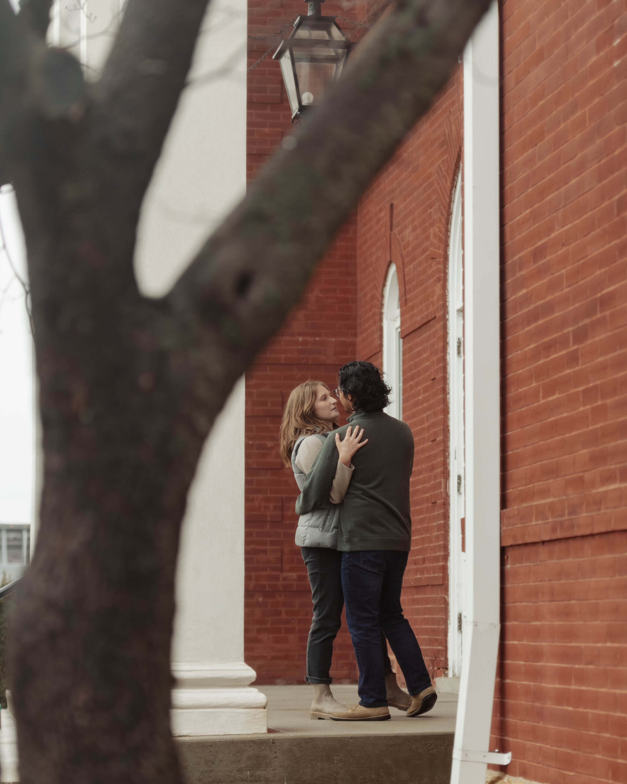 A man and woman dance on the steps of a courthouse during their engagement session. They are looking at each other.