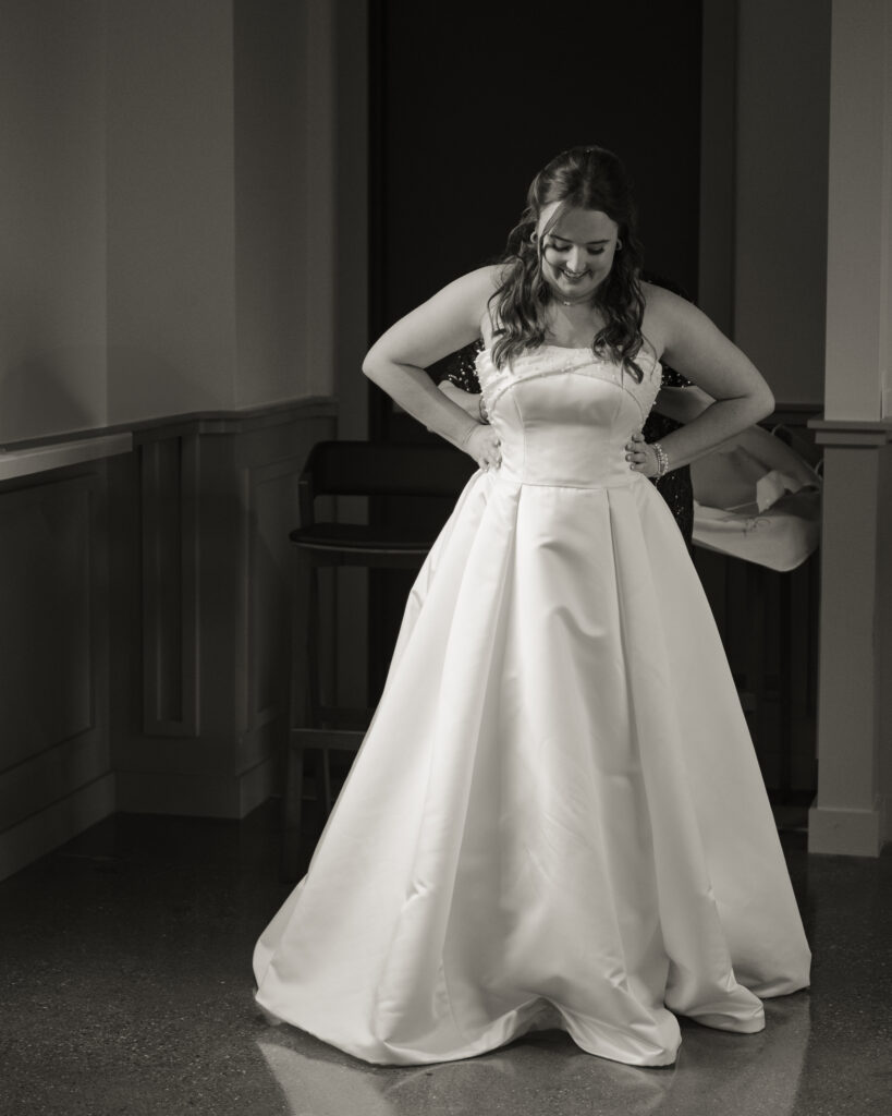 A romantic black and white portrait of a bride getting into her wedding dress before her catholic wedding.