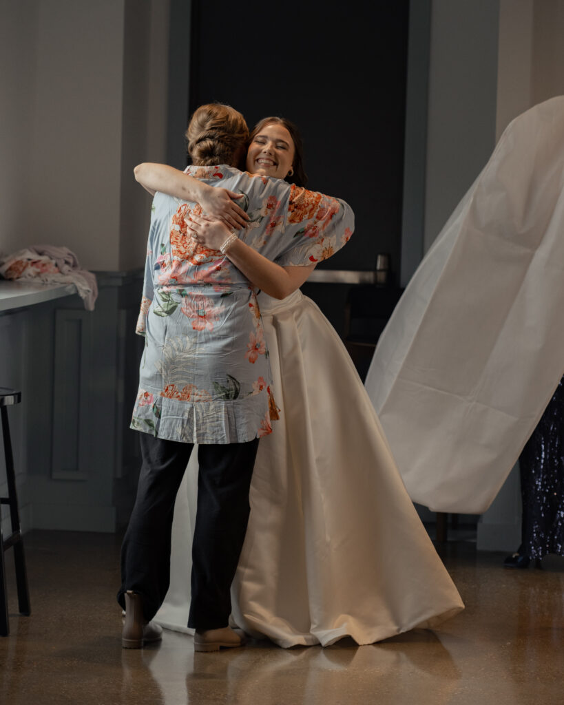 A bride hugs one of her bridesmaids after she gets into her wedding dress.