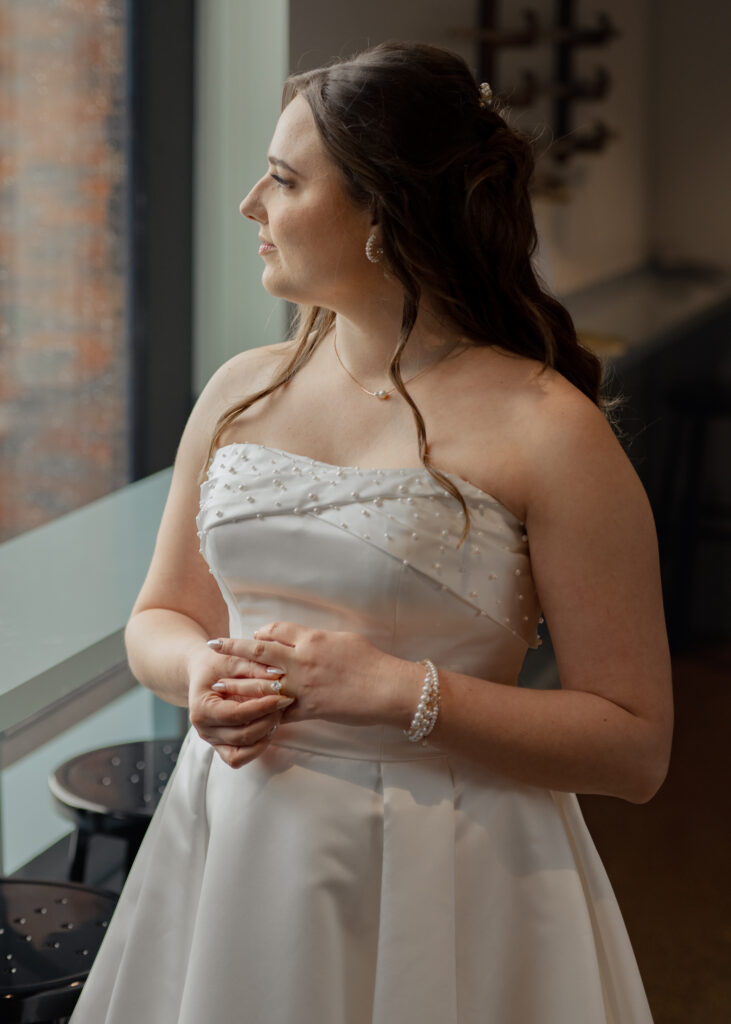 A catholic bride stares out the window before her downtown dayton catholic wedding.