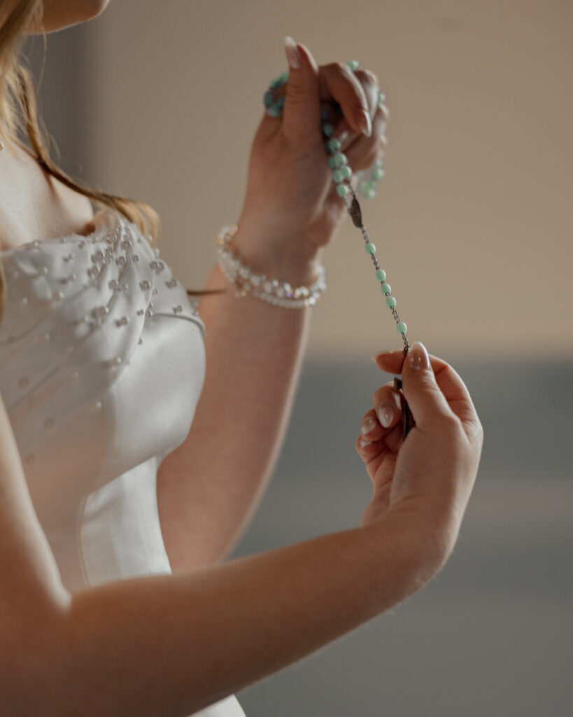 A bride shows off her grandmother's rosary that will be wrapped around her wedding bouquet for her catholic wedding.
