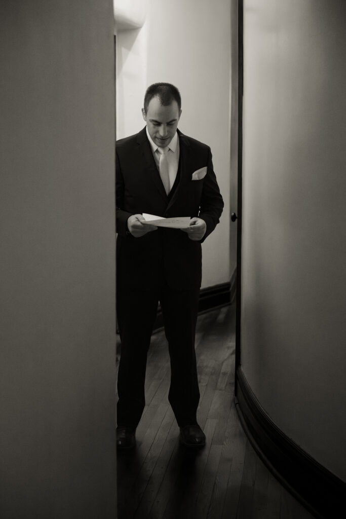 A groom reads a letter from his catholic bride in the back hallway of a historic catholic church, Our Lady of the Rosary, in downtown Dayton, Ohio