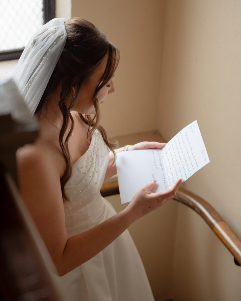 A catholic bride reads a letter from her soon to be husband in the stairwell of a historic catholic church.