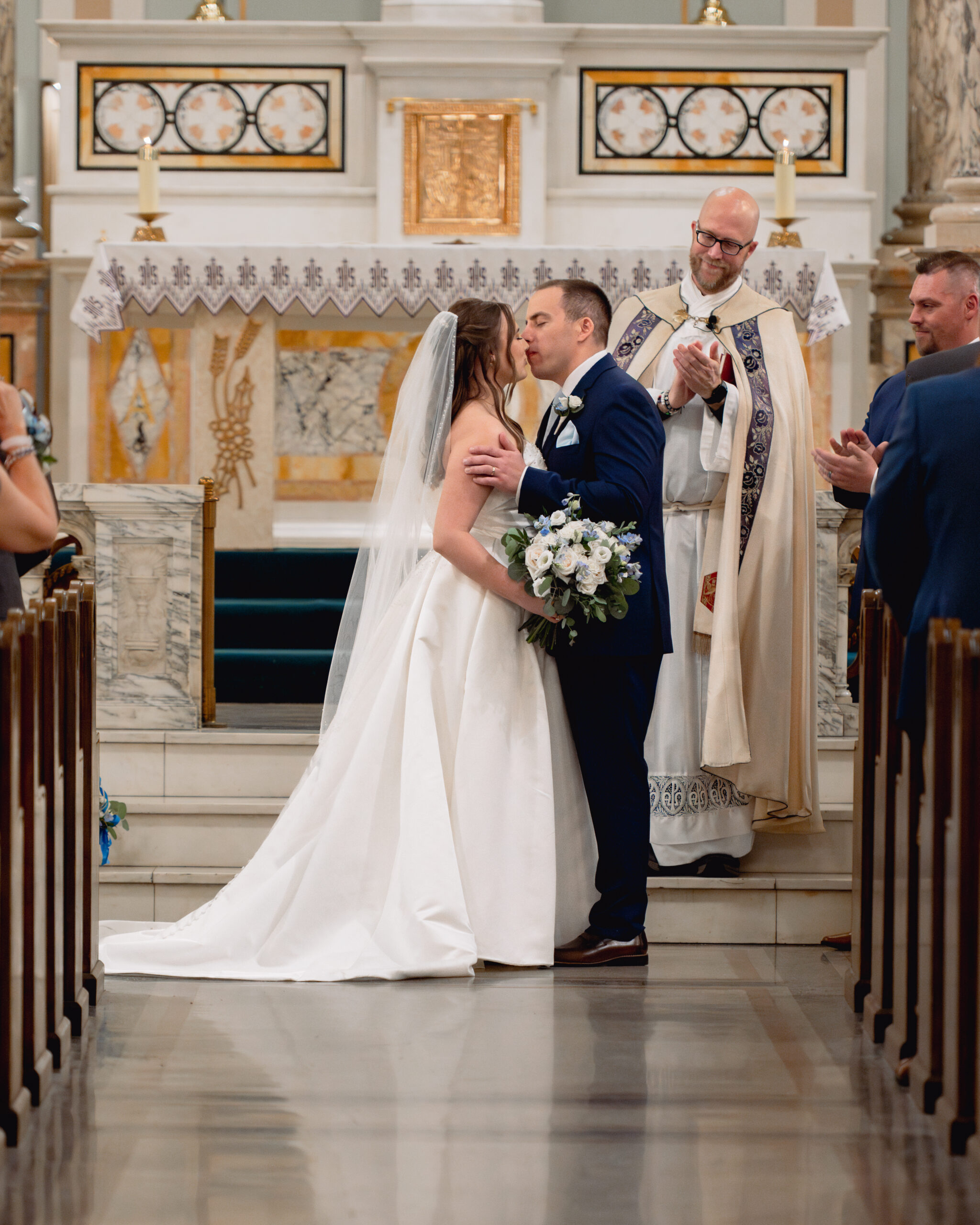A catholic bride and groom exchange a first kiss during their catholic wedding ceremony at Our Lady of the Rosary in Dayton, Ohio.