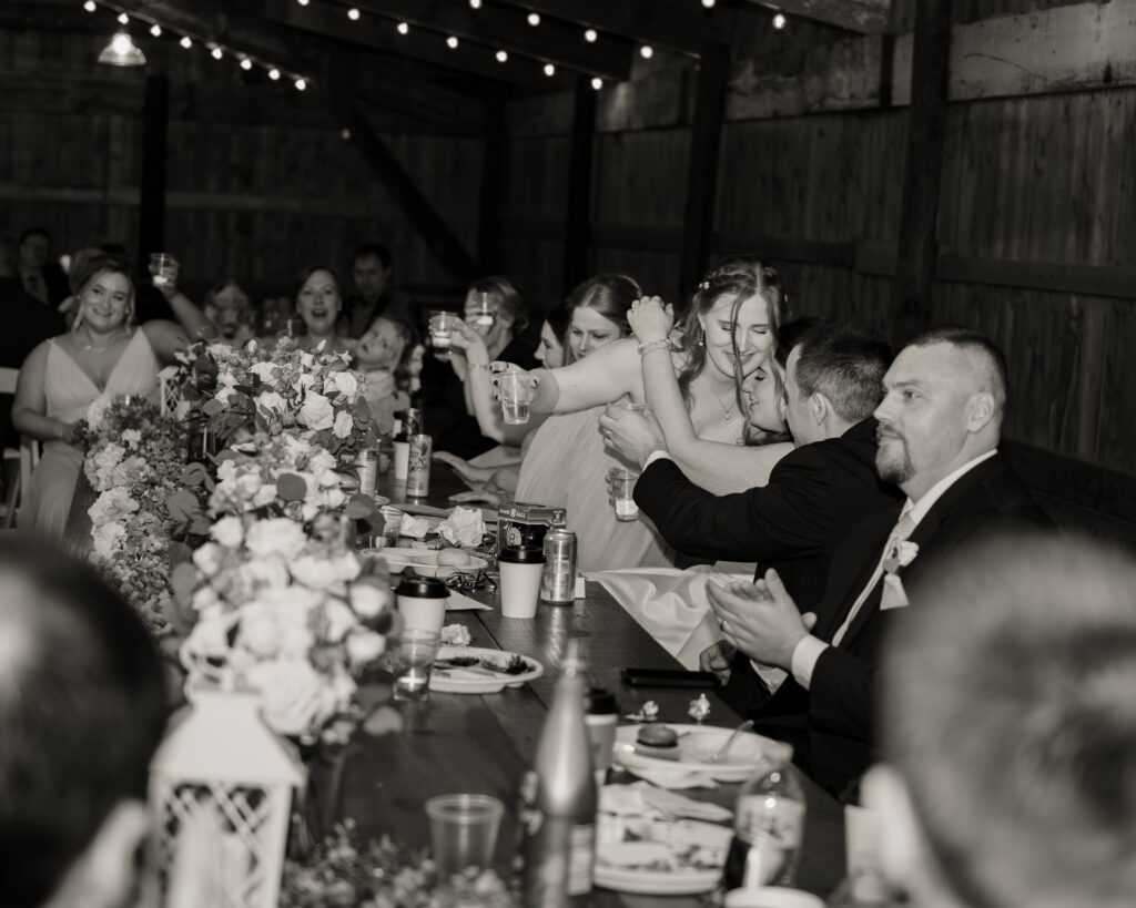A maid of honor gives the bride a hug as the whole wedding reception toasts after her speech.