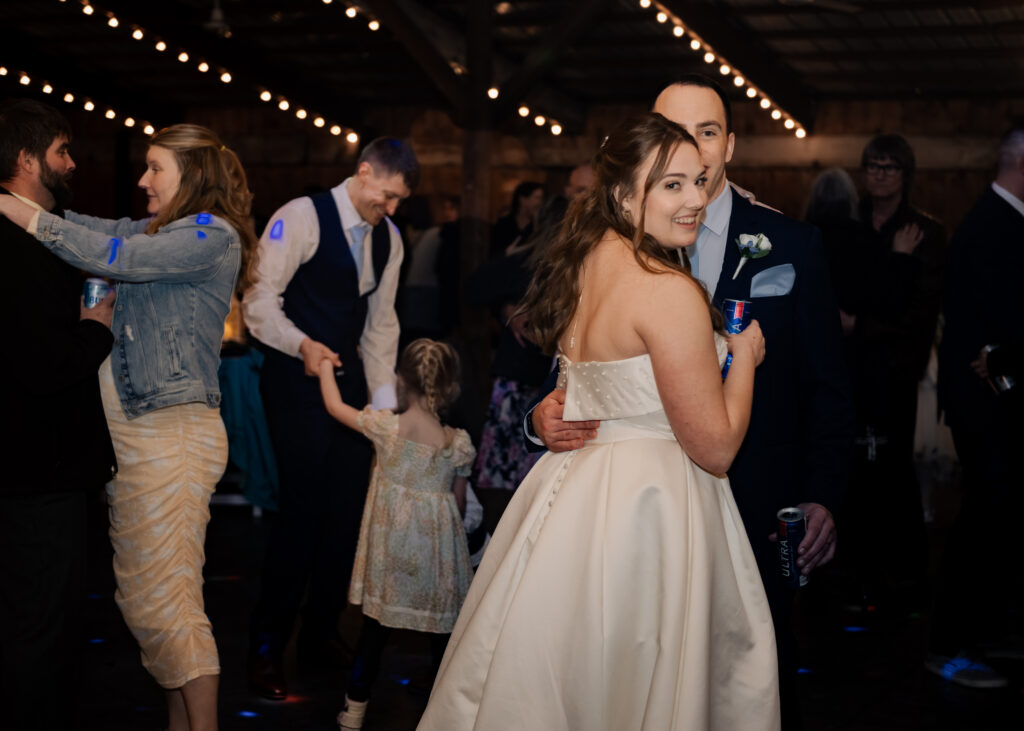 A bride and groom dance and smile at the camera during their catholic wedding reception in Piqua, Ohio.
