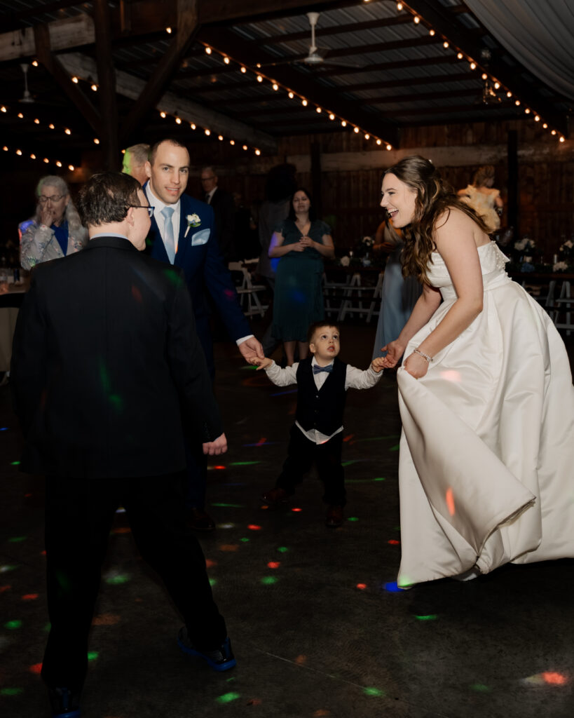 A bride and groom dance with their guests on the dance floor of their catholic wedding reception in Piqua, Ohio.