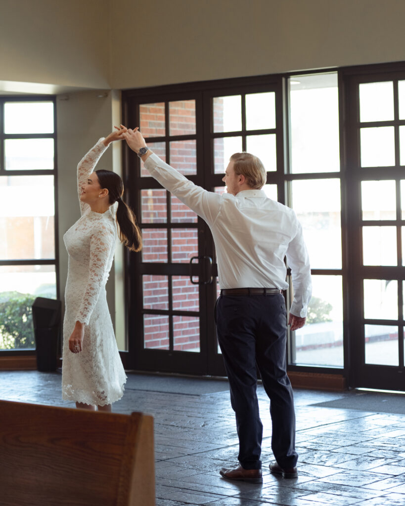 A catholic dances in the narthex of St. Mary's Catholic church in Jackson, Tennessee during their sunny engagement session ahead of their catholic wedding.