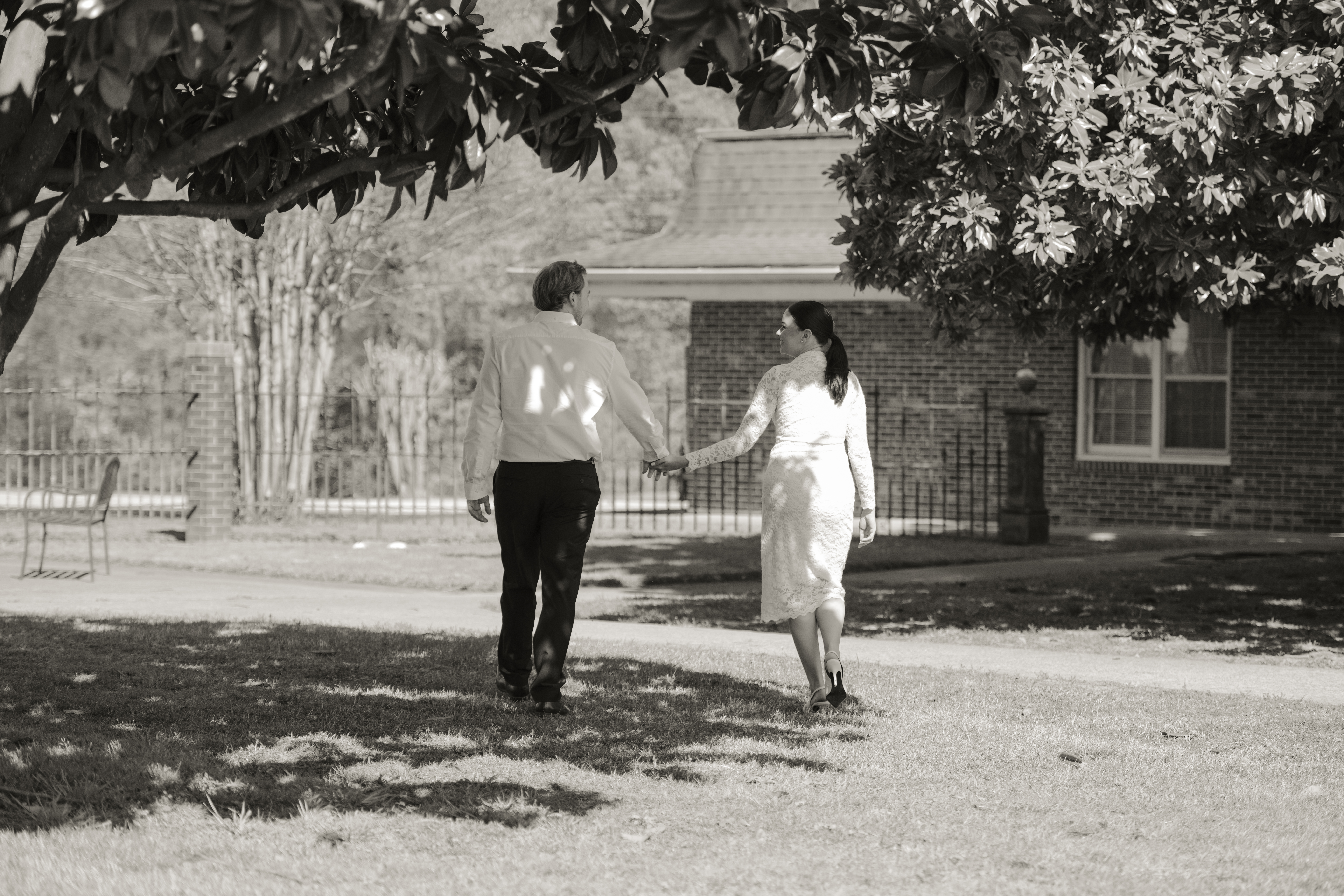 A couple walks outside St. Mary's Catholic church in Jackson, Tennessee during their sunny engagement session ahead of their catholic wedding.