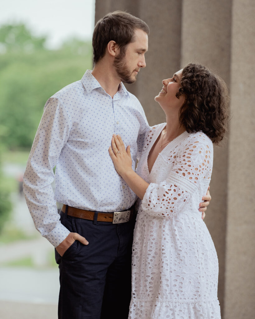 A catholic couple looks lovingly at one another during their engagement at centennial park in nashville, tn