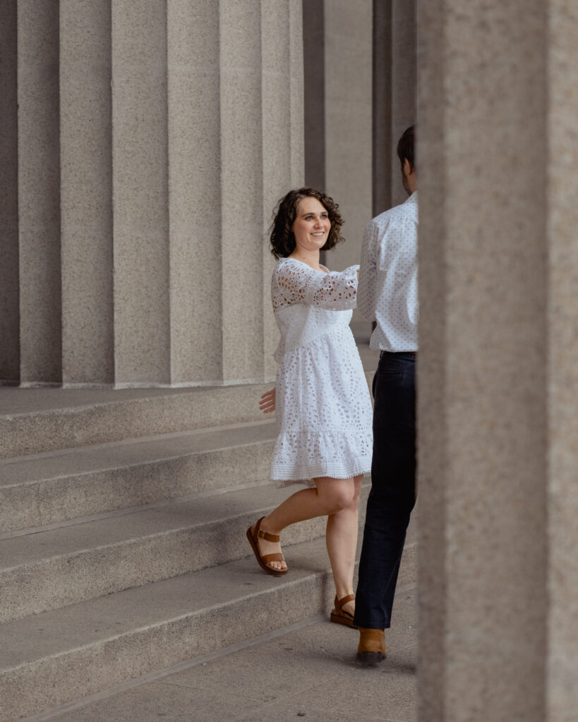 A catholic bride is led down the steps of the parthenon during a catholic engagement session at centennial park in Nasvhille, tn