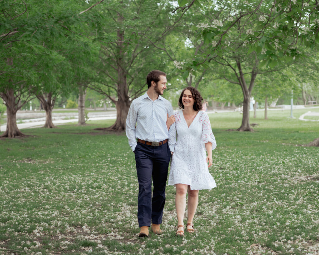 A catholic bride and groom walk through centennial park in Nashville, TN during their catholic engagement session
