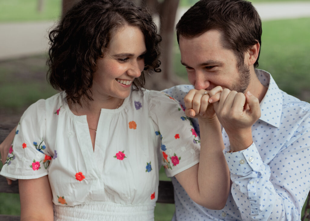 a catholic groom kisses the ring of his soon to be bride during their catholic engagement session at centennial park in nashville tennessee