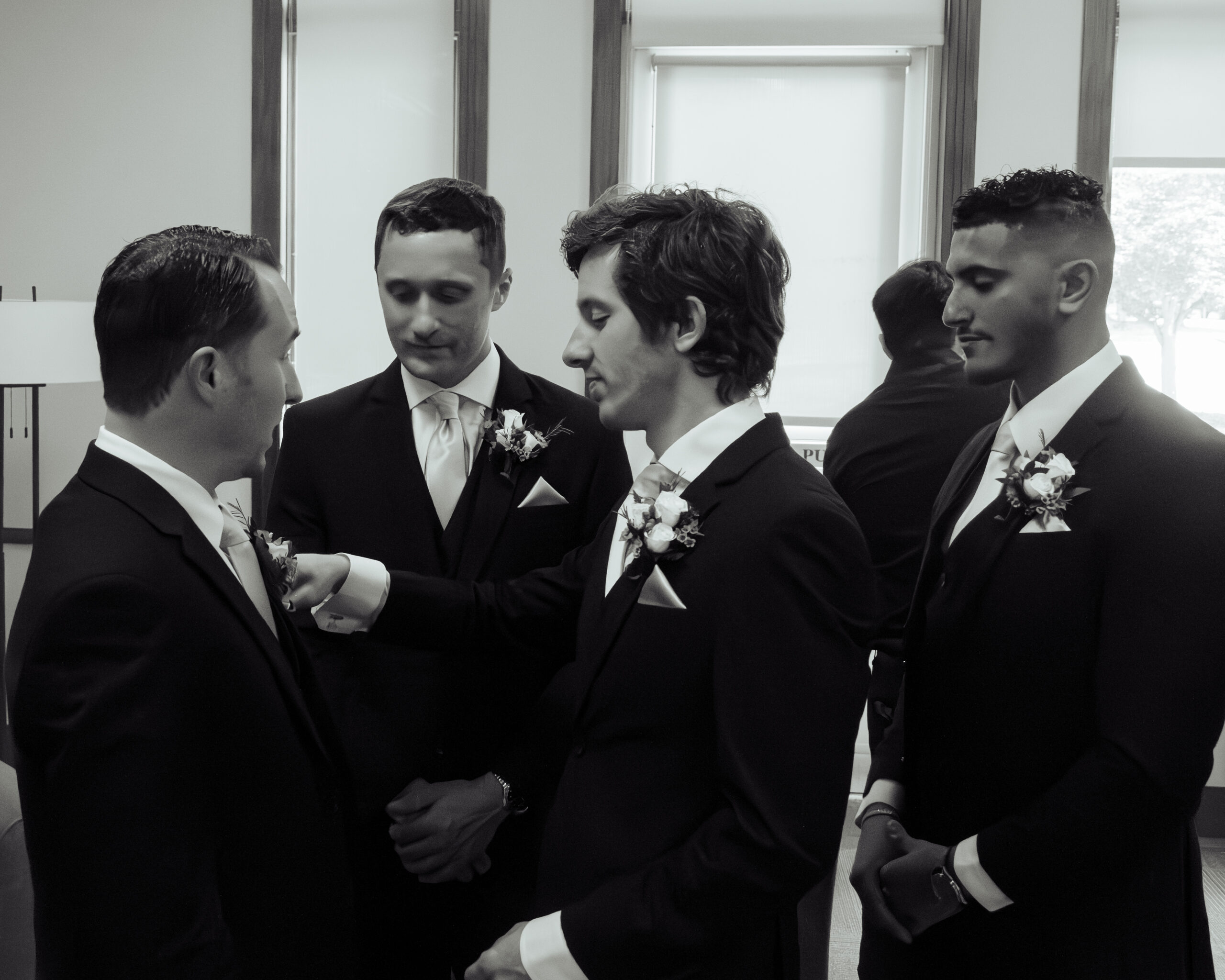 Groomsmen adjust each other's suits ahead of a nashville catholic wedding mass at Holy family catholic church.
