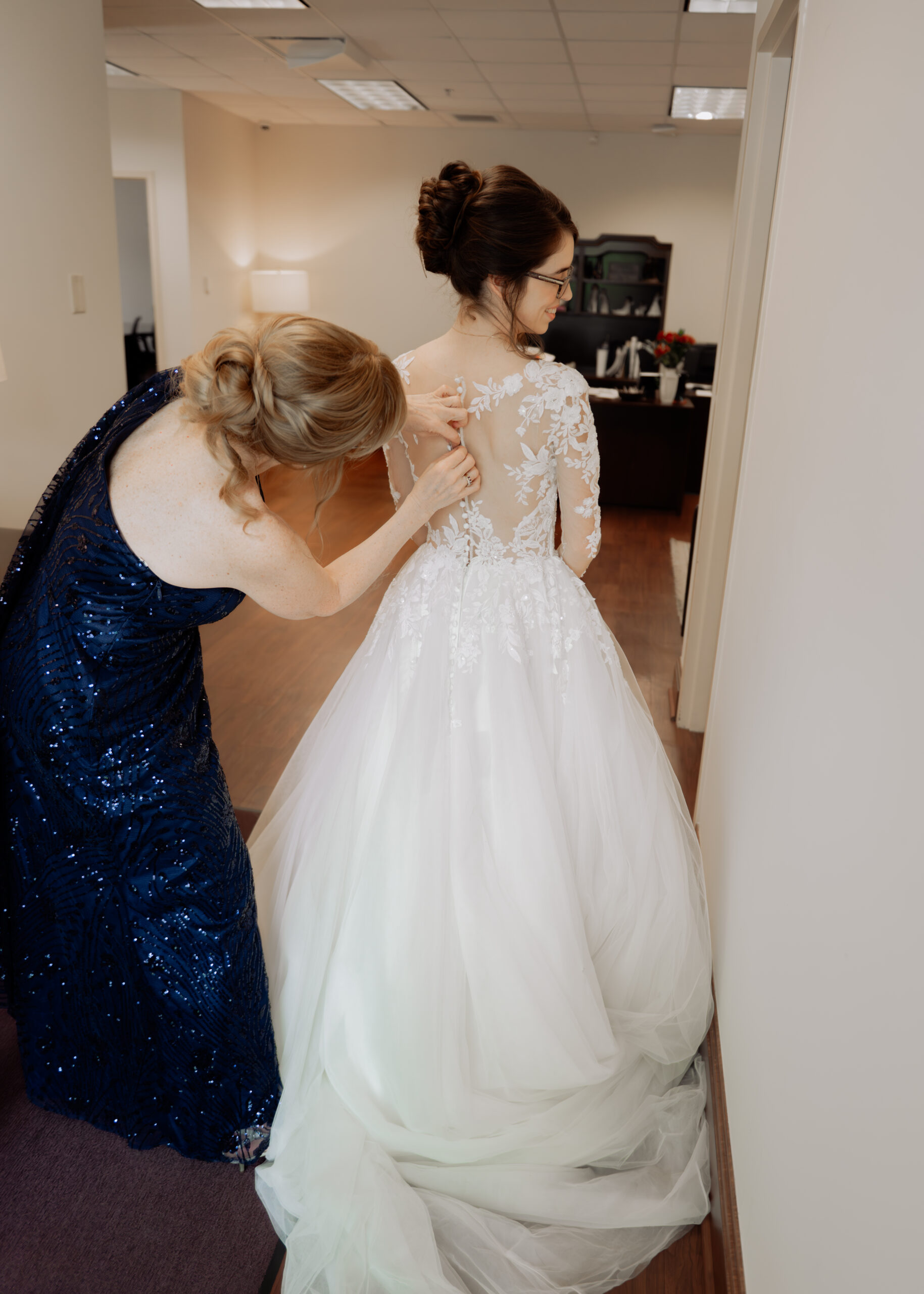 A catholic bride get's her dress buttoned by her mother at Holy Family catholic church in Nashville ahead of her catholic wedding Mass.