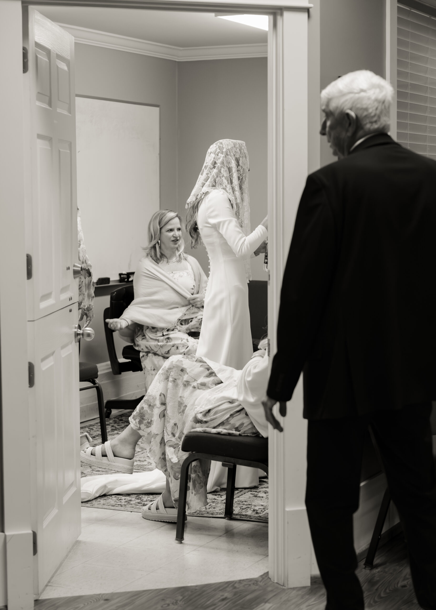 A catholic bride in a traditional catholic veil prepares for her wedding Mass with her close family at st. mary of the seven sorrows in downtown nashville.