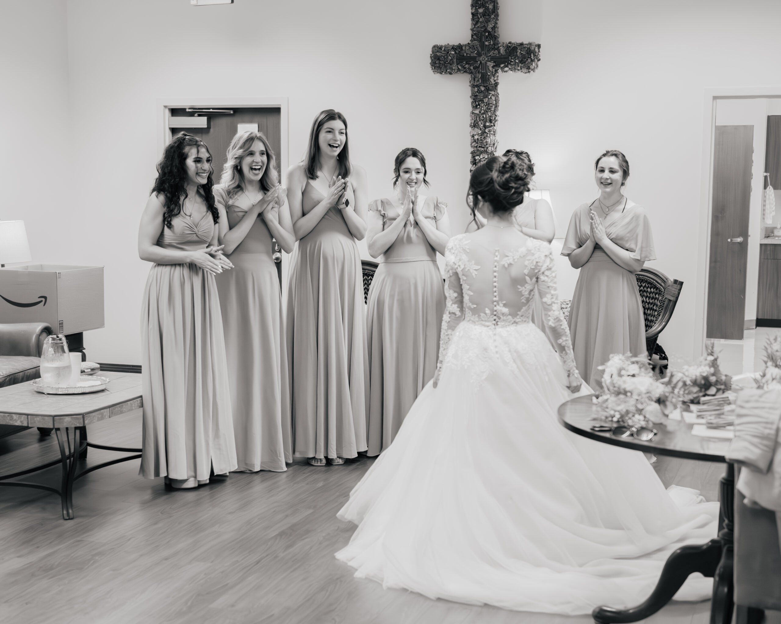 Bridesmaids look excitedly at a catholic bride as she shows off her wedding dress at Holy Family catholic church in Nashville ahead of her catholic wedding Mass.