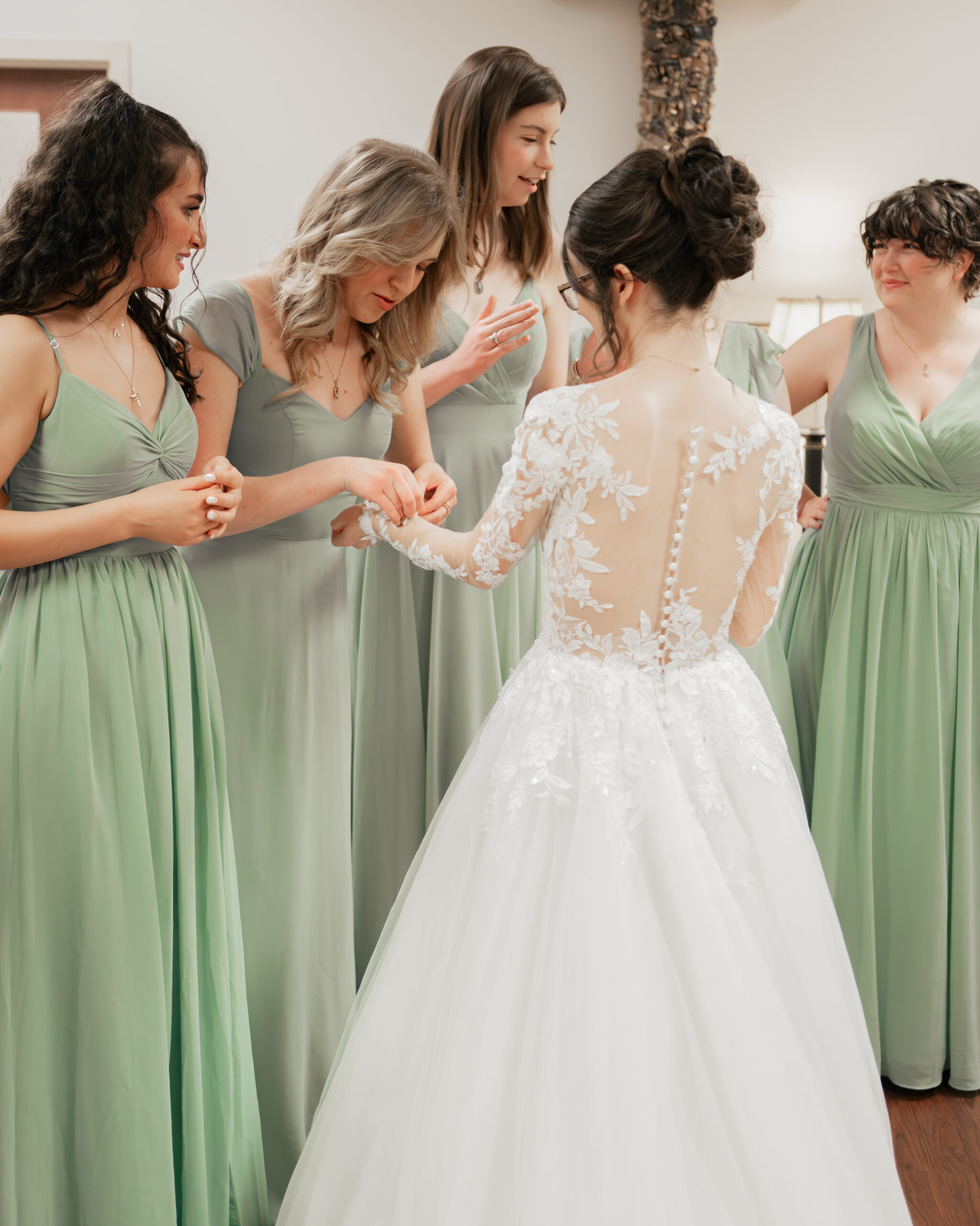 Bridesmaids help a catholic bride button her dress at Holy Family catholic church in Nashville ahead of her catholic wedding Mass.