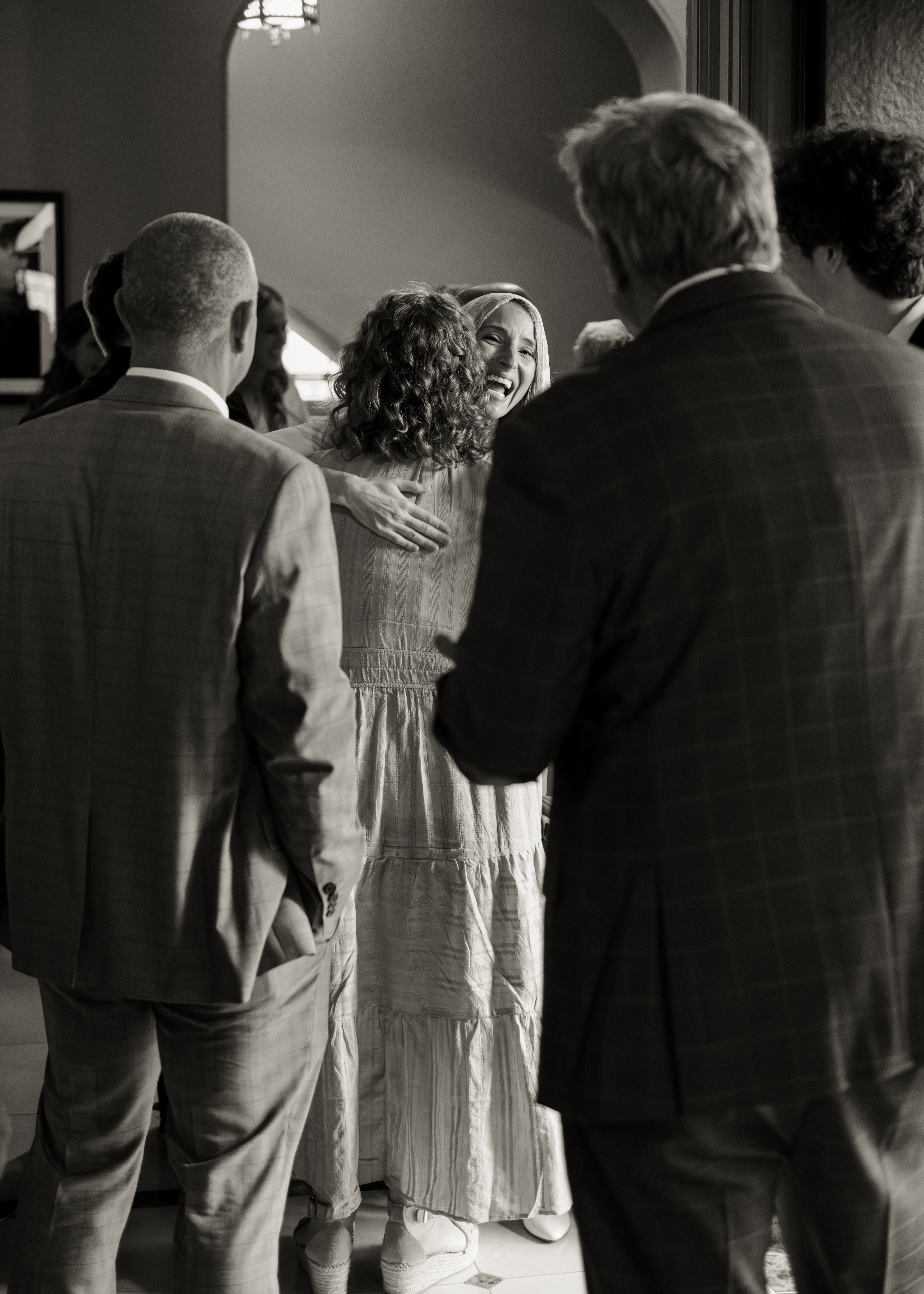 Family members hug a laughing catholic bride after her catholic wedding Mass at St. Mary's of the Seven sorrows in downtown Nashville, tn