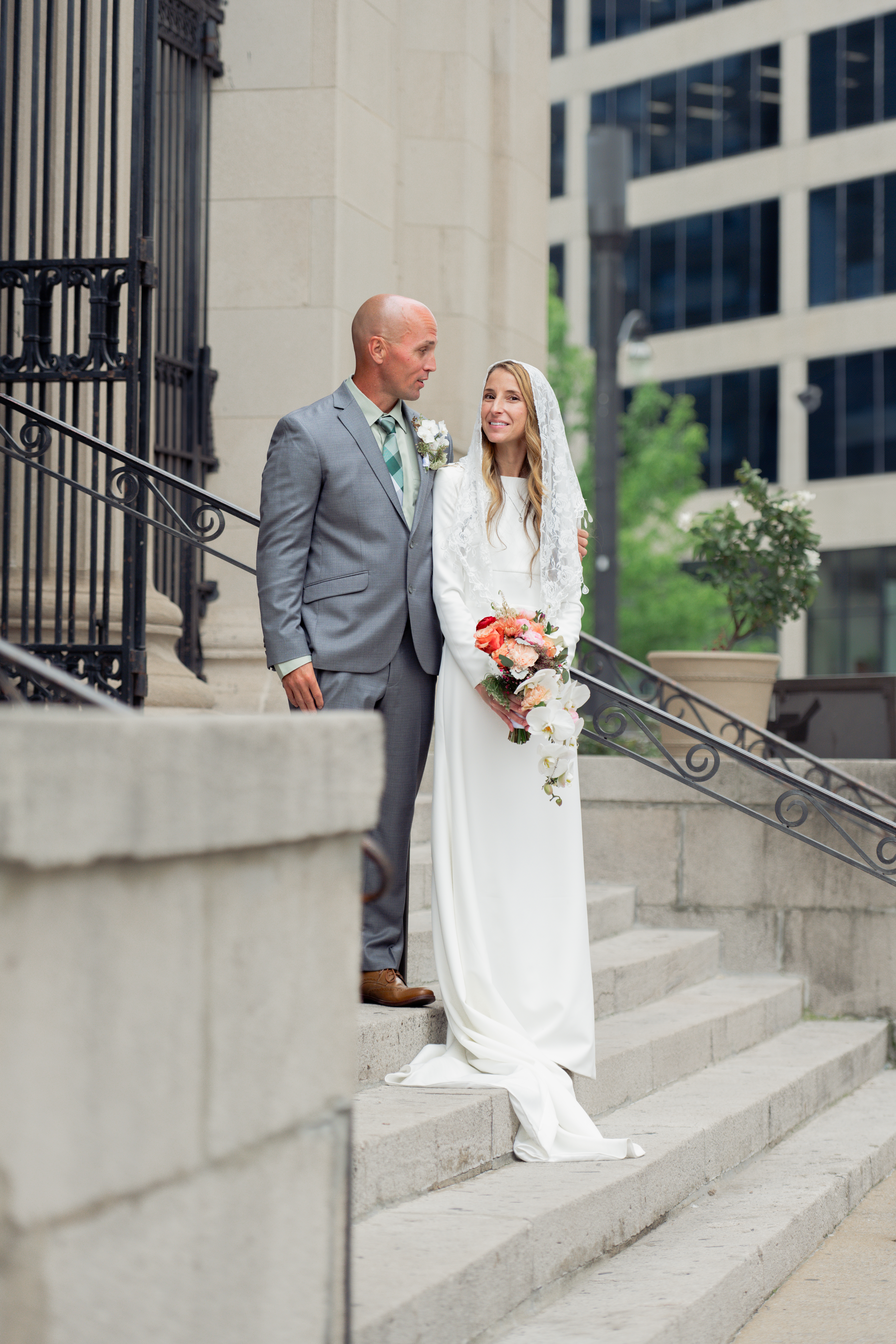 A catholic bride and groom prepare for a formal portrait on the steps of St. Mary's of the Seven sorrows in downtown Nashville, tn after a catholic wedding Mass