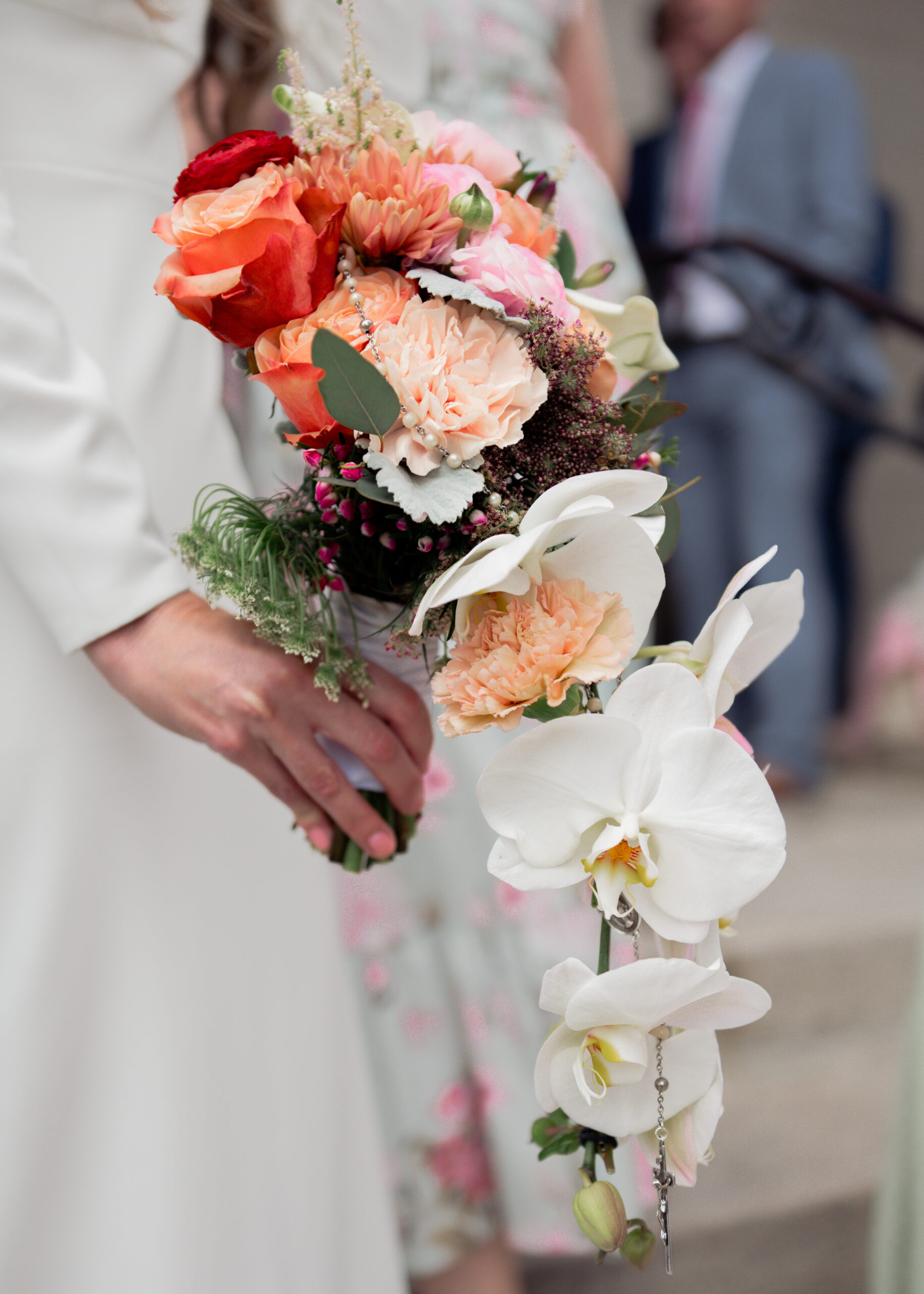 A catholic bridal bouquet with orchids and a rosary woven through it outside of St. Mary's in downtown Nashville after a catholic wedding Mass