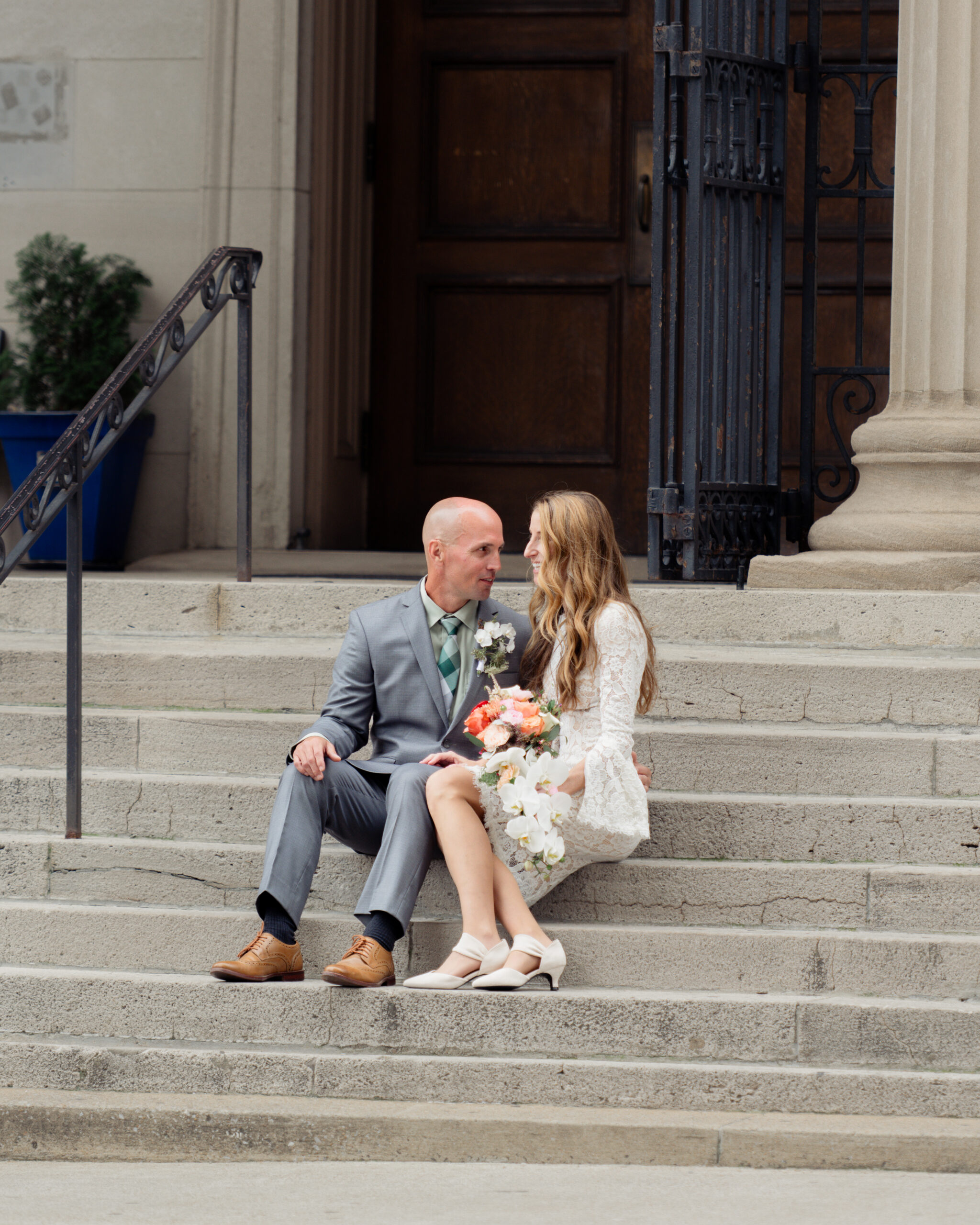 A catholic bride and groom laugh together on the steps of St. Mary's in downtown Nashville after their catholic wedding Mass