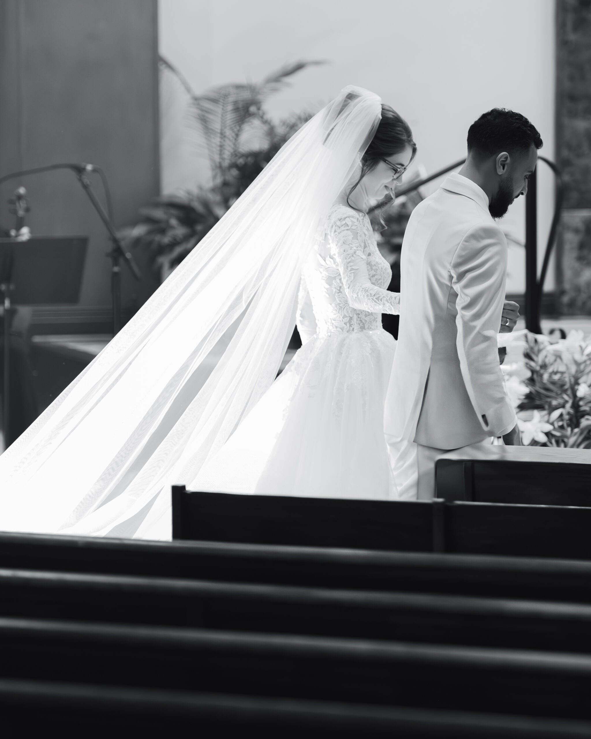 A bride and groom walk back from giving flowers to Mary and consecrating their marriage to her during a catholic wedding Mass at Holy Family Catholic Church in Brentwood, TN.