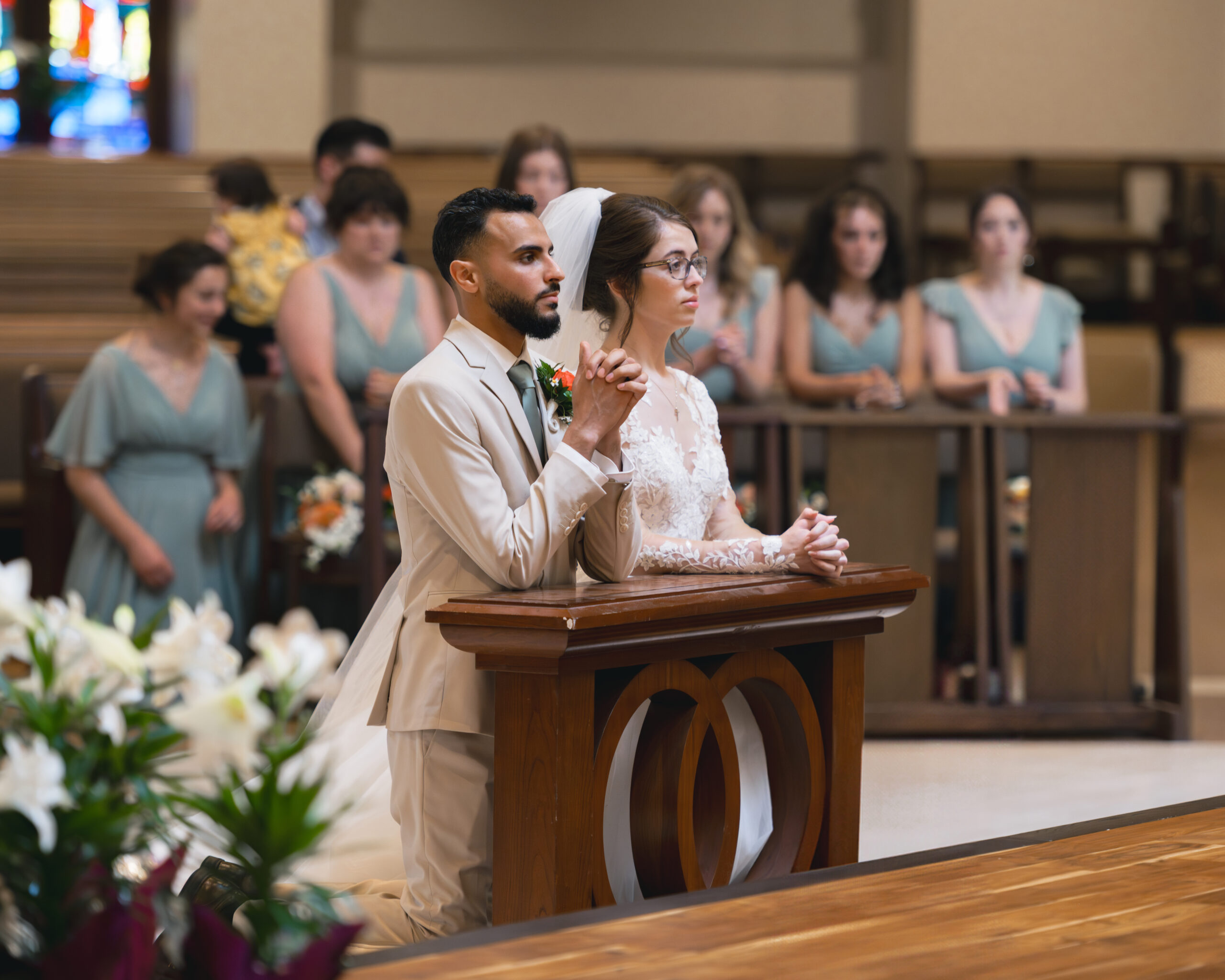 A catholic bride and groom kneel and pray during a catholic wedding Mass at Holy Family Catholic Church in Brentwood, TN.