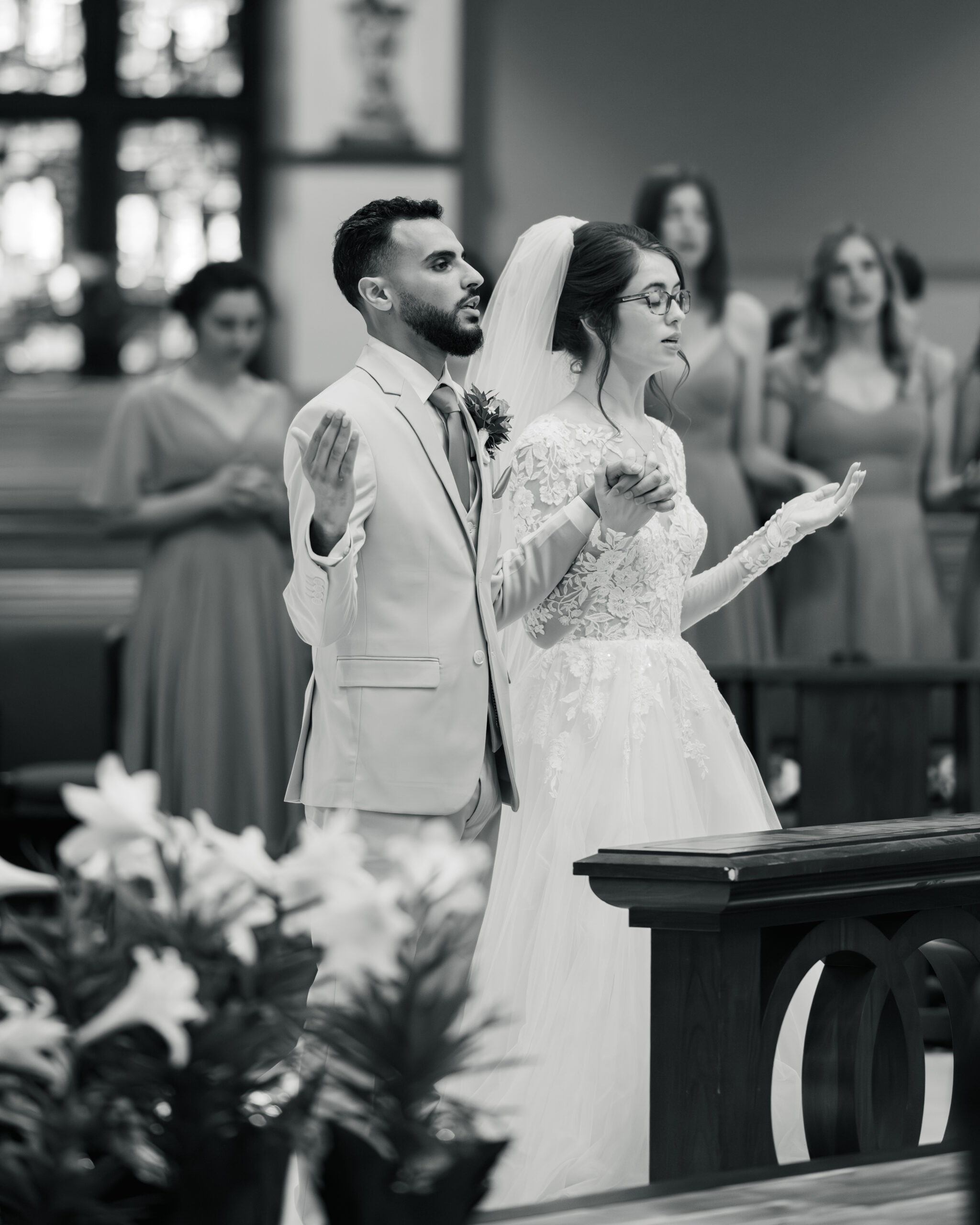 A bride and groom raise their hands in prayer during a catholic wedding Mass at Holy Family Catholic Church in Brentwood, TN.