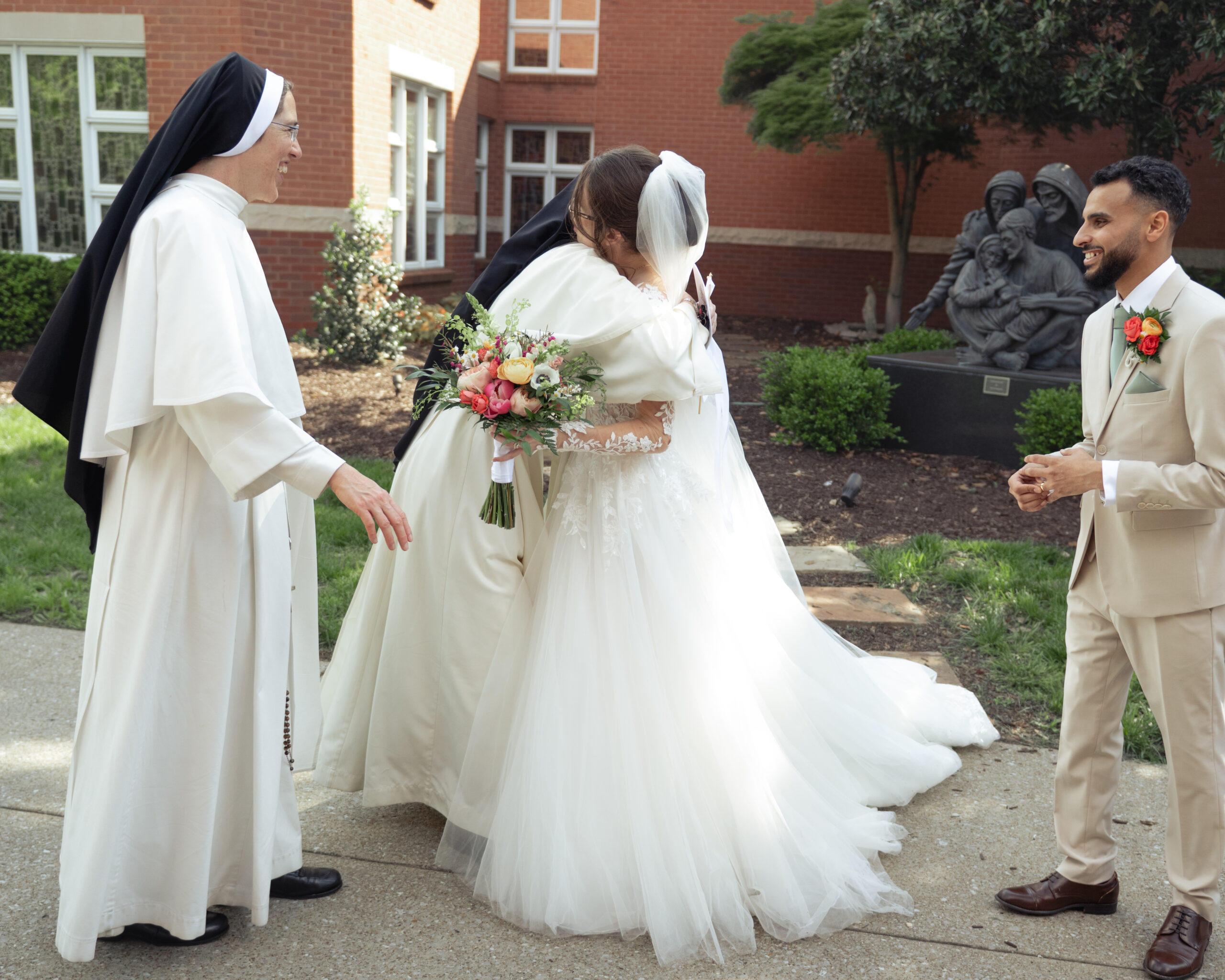 A catholic bride and groom hug two Domincan sisters of st. cecilia after their catholic wedding mass at holy family catholic church in brentwood, tn.