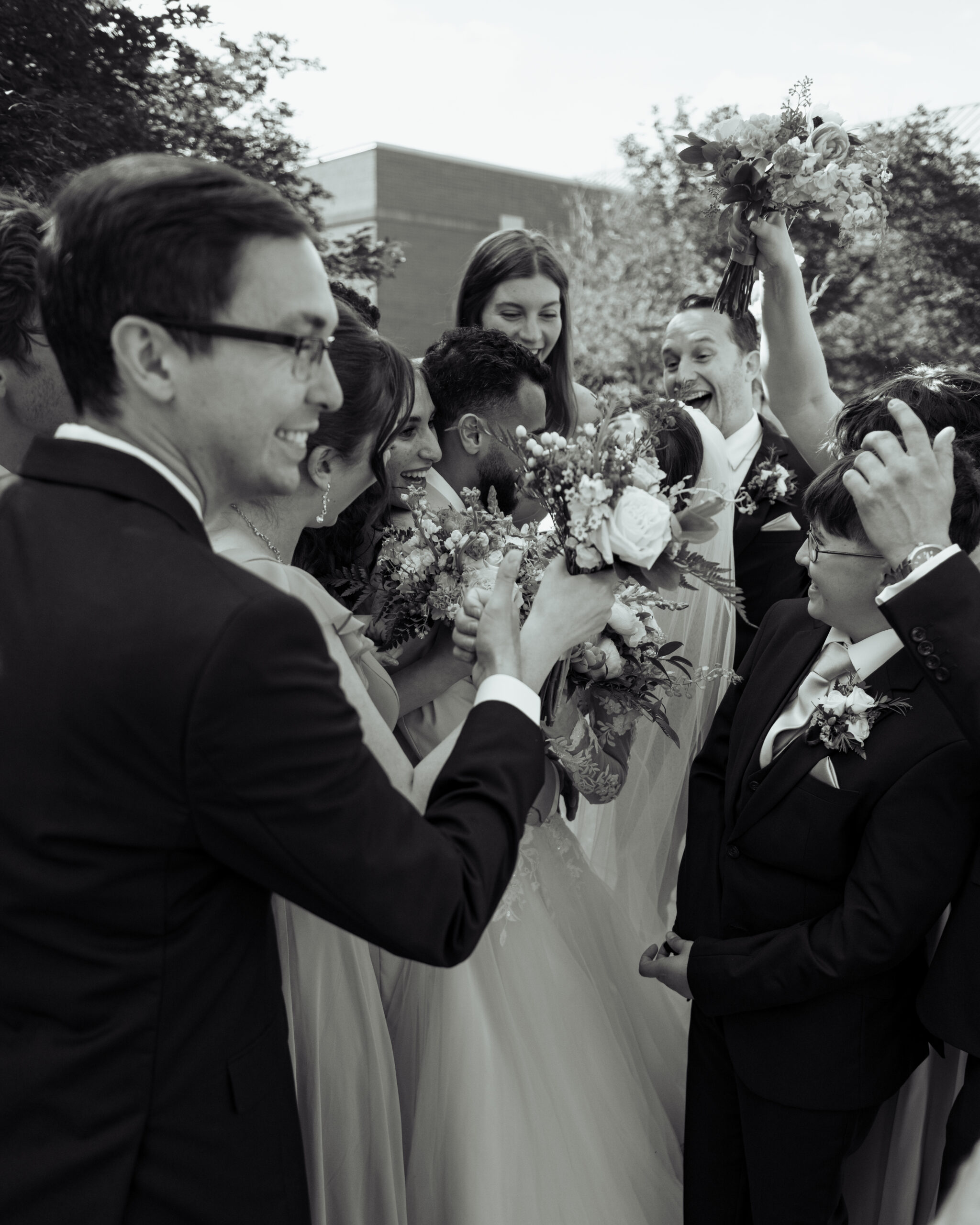 A catholic groom and bride kiss each other as their friends surround them after their catholic wedding at holy family catholic church in brentwood, tn