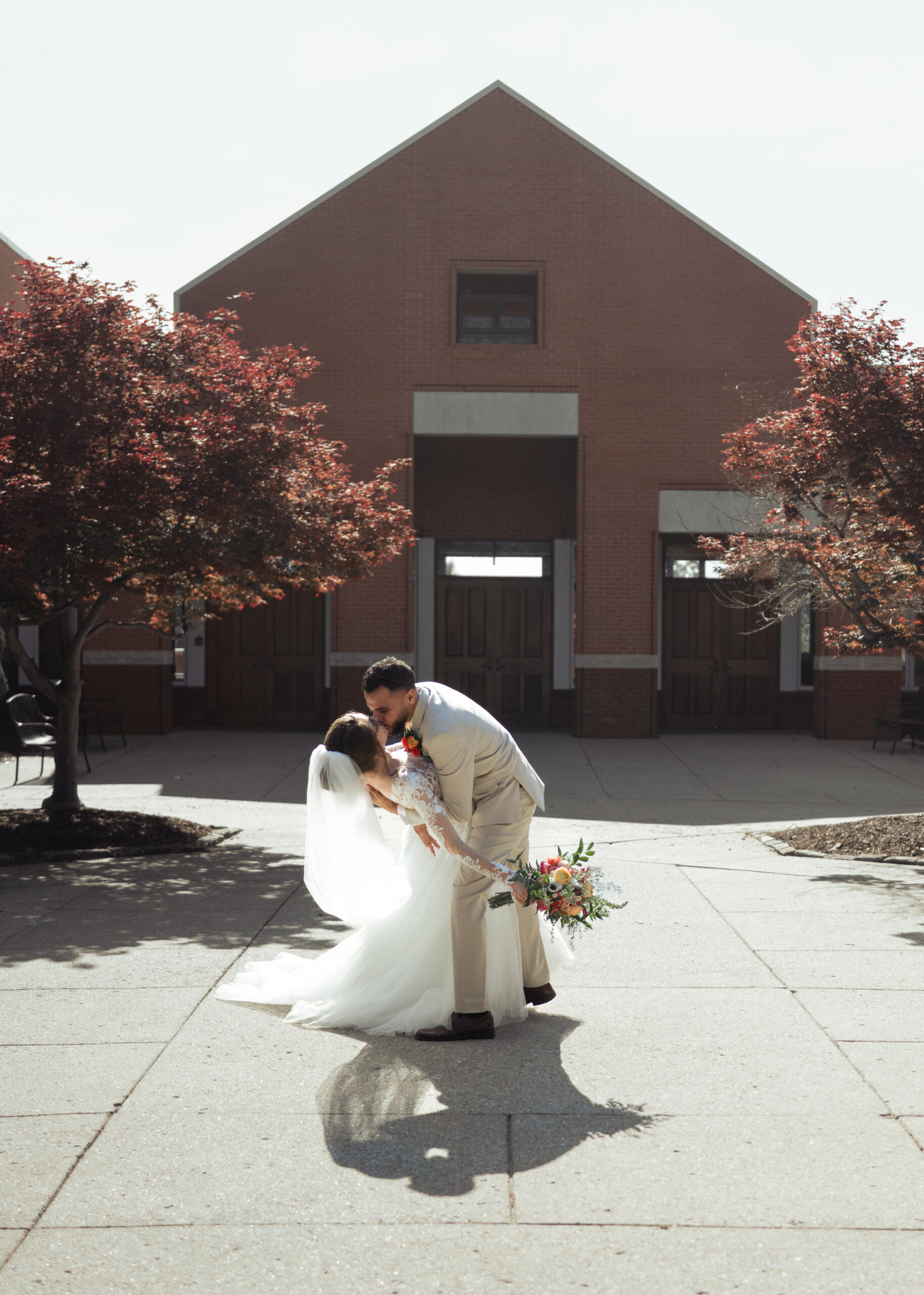 A catholic bride and groom share a dip kiss outside of holy family catholic church after their nashville catholic wedding mass.