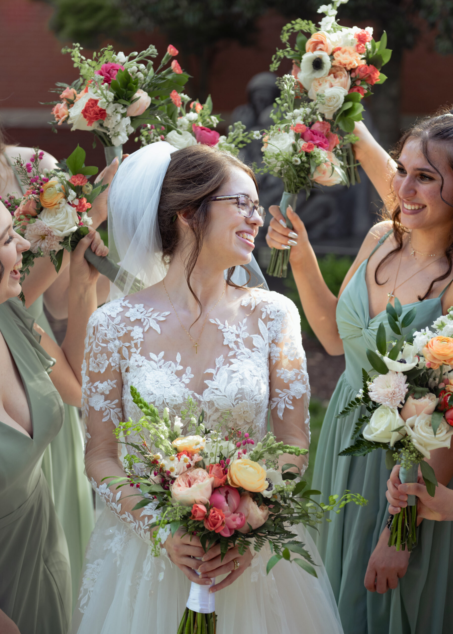 A bride grins at her bridesmaids who surround her after her catholic wedding at holy family catholic church in brentwood, tn
