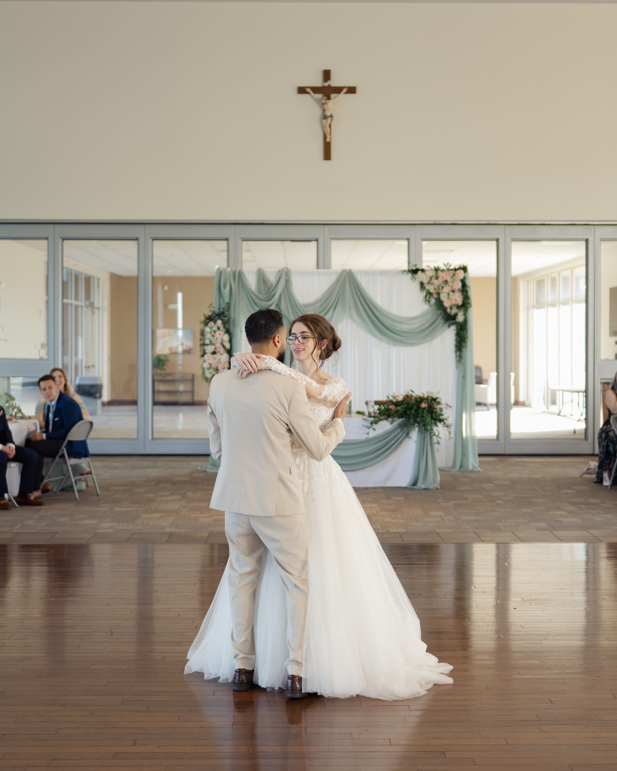 A catholic bride and groom share a first dance under a crucifix at a catholic wedding reception at holy family catholic church in brentwood, tn