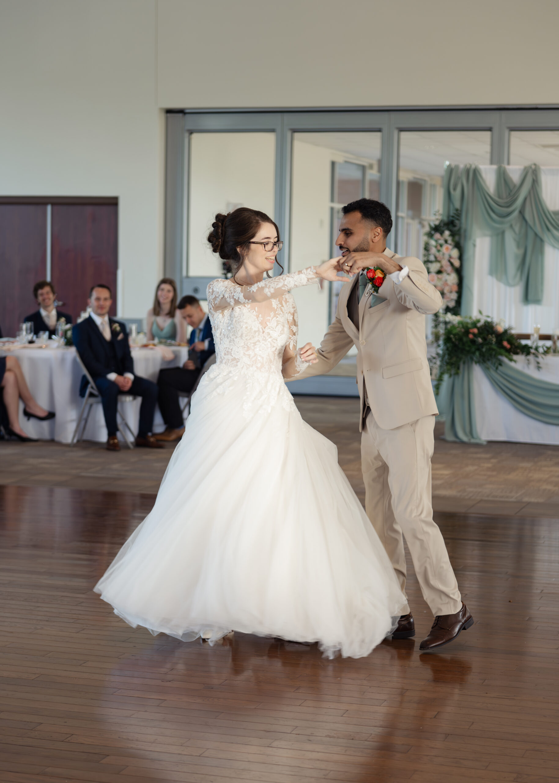 A catholic bride and groom share a first dance in front of their friends at a catholic wedding reception at holy family catholic church in brentwood, tn