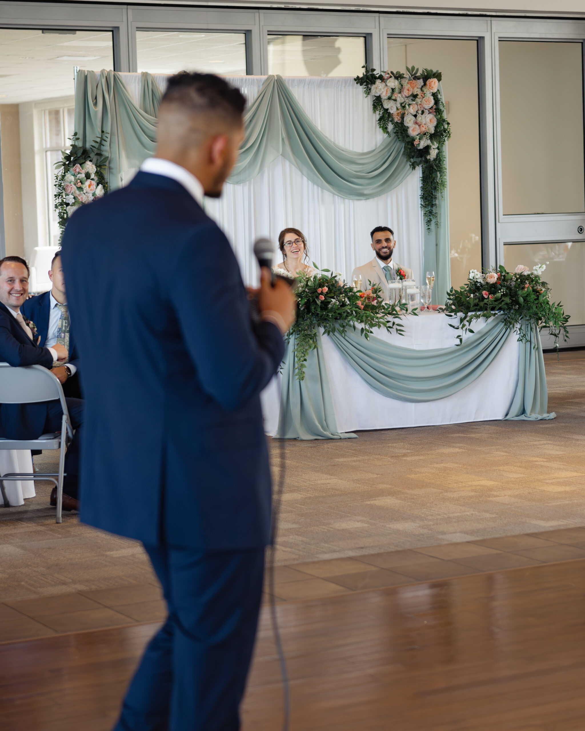 The best man makes the bride and groom laugh during his speech at at a catholic wedding reception at holy family catholic church in brentwood, tn