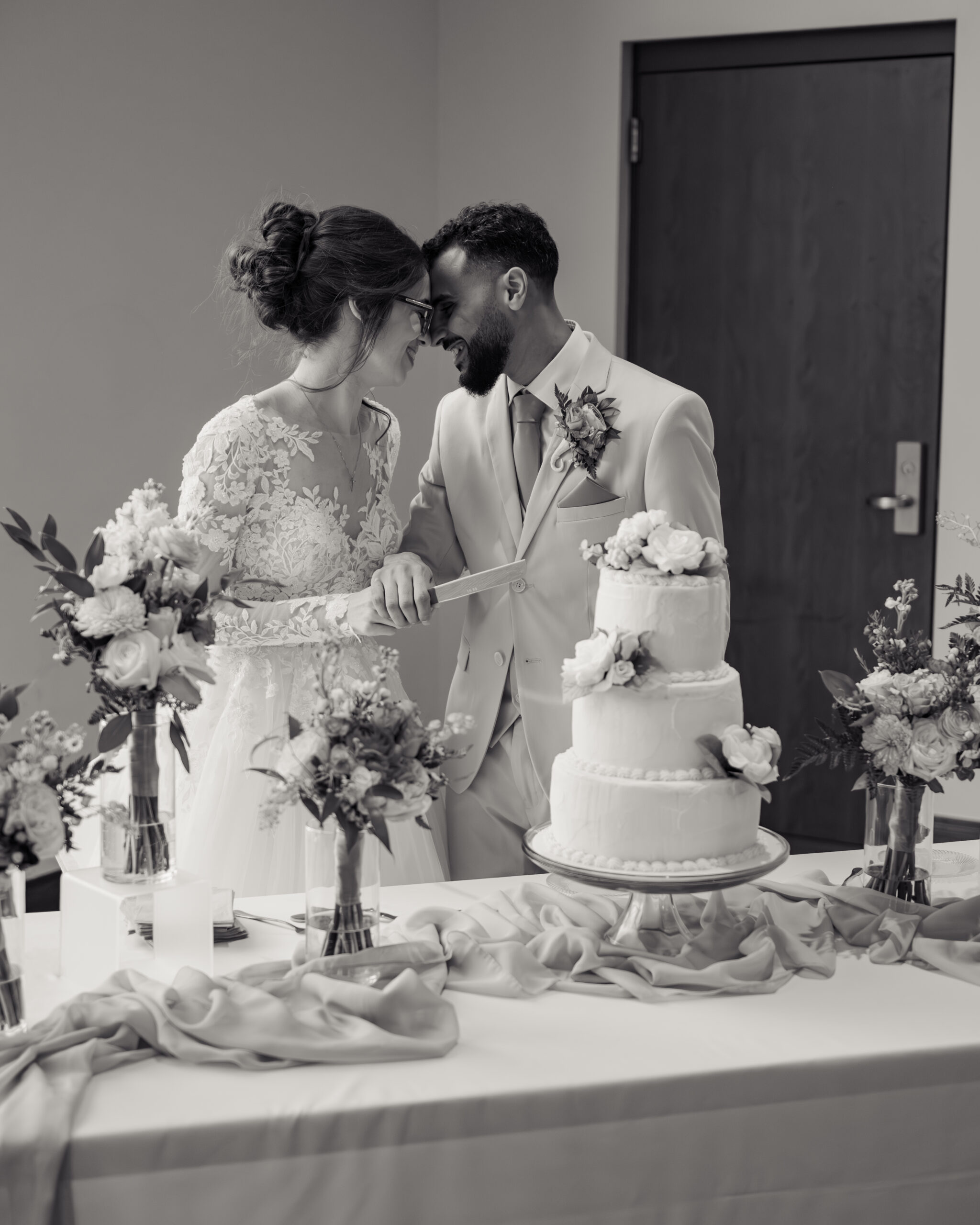 A catholic bride and groom share an intimate moment cutting cake at a catholic wedding reception at holy family catholic church in brentwood, tn