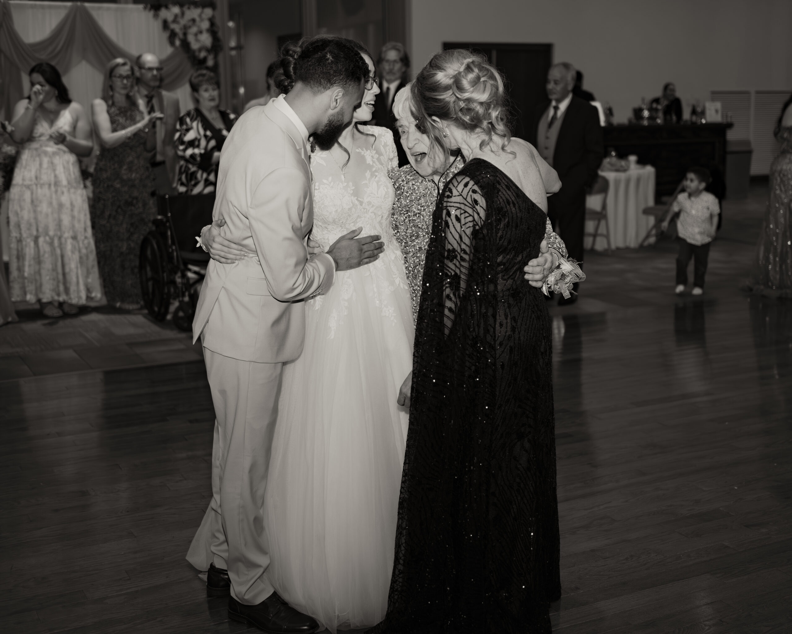 A catholic bride and groom laugh with the mother of the bride and the bride's grandmother at A catholic bride and groom share an intimate moment cutting cake at a catholic wedding reception at holy family catholic church in brentwood, tn