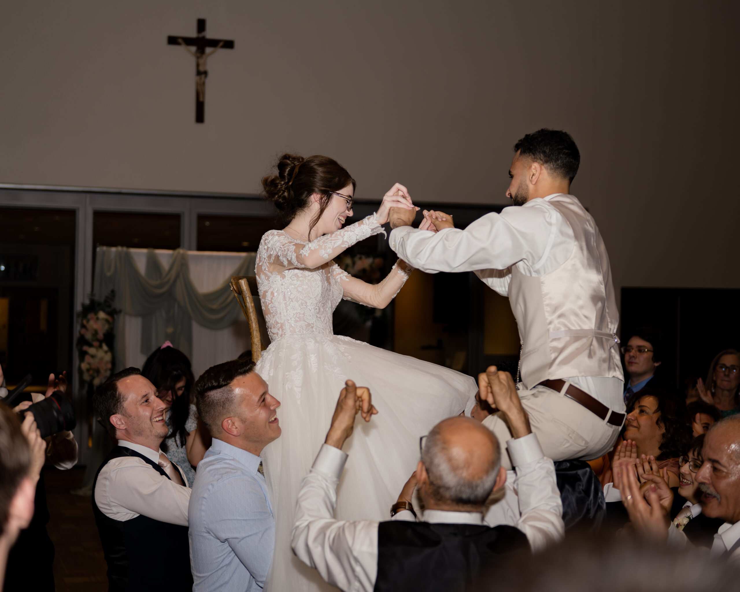 Wedding guests lift up the bride and groom during a dance at a catholic wedding reception at holy family catholic church in brentwood, tn