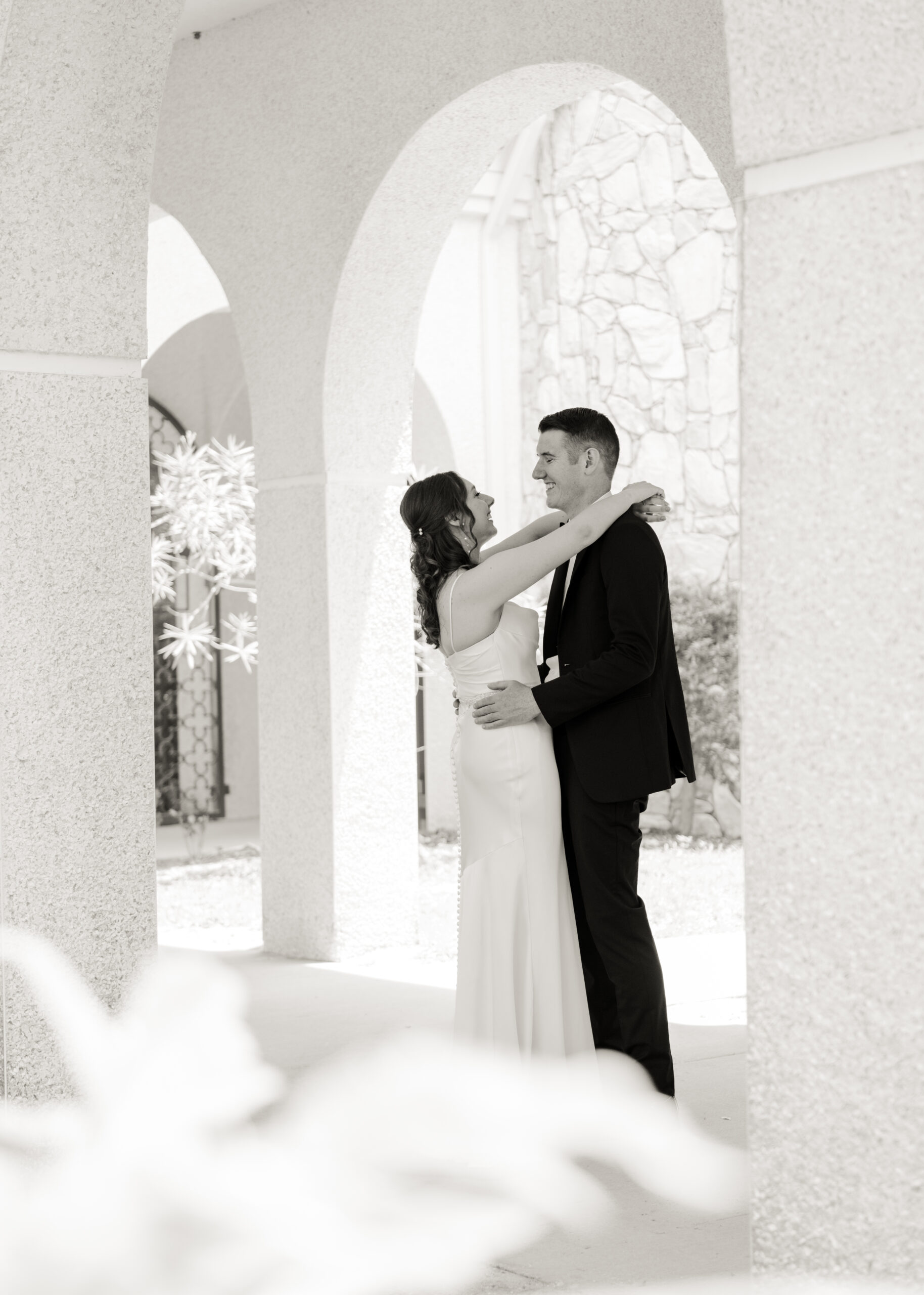Romantic black and white portrait of a Catholic couple sharing a private moment beneath the arched walkways of St. Anastasia’s Catholic Church before their nuptial mass.