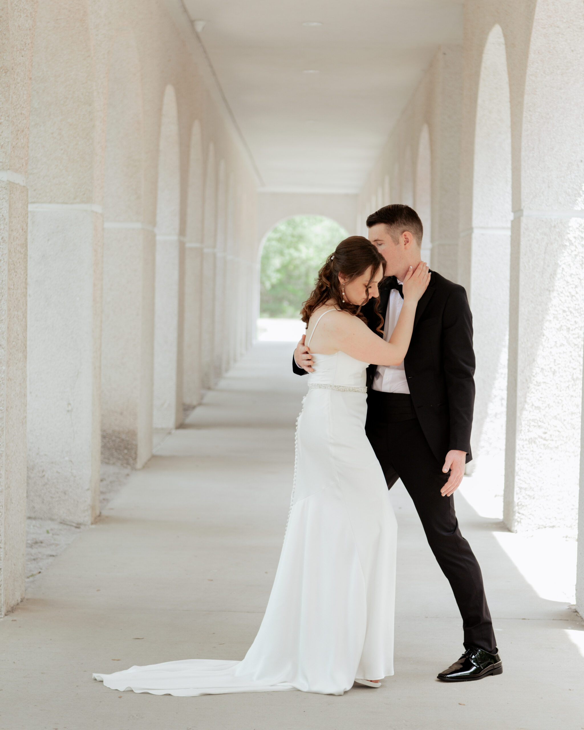 Elegant portrait of a Catholic bride and groom embracing under the arches of St. Anastasia’s Catholic Church, preparing for their traditional Catholic wedding ceremony.