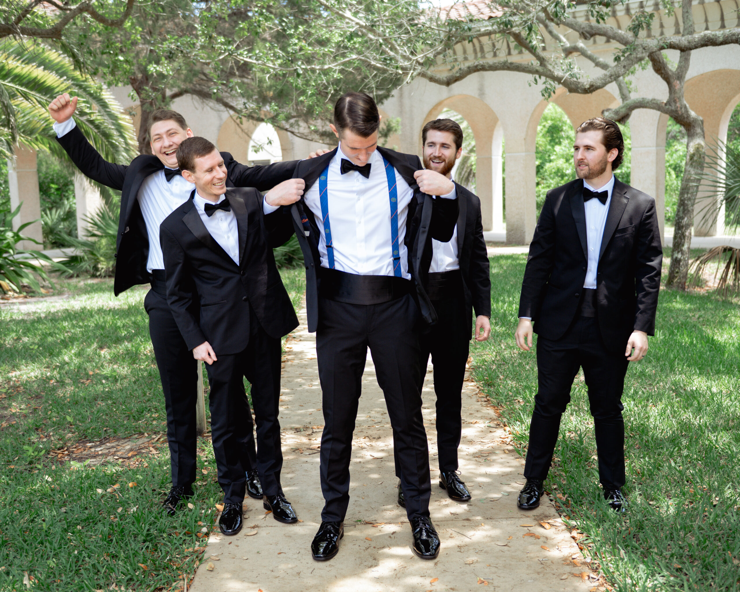 Groomsmen cheer on a catholic groom as he shows off his Florida gators suspenders on his wedding day