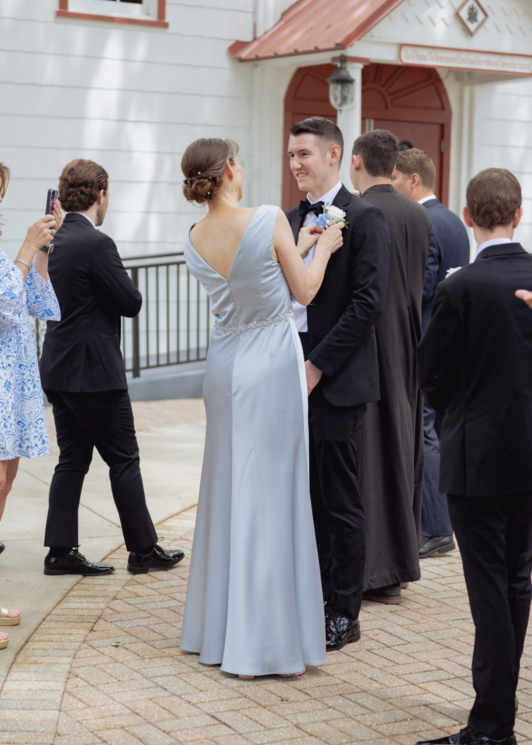 the mother of the bride adjusts the groom's suit before his catholic wedding mass at st. ambrose catholic church in elkton, florida