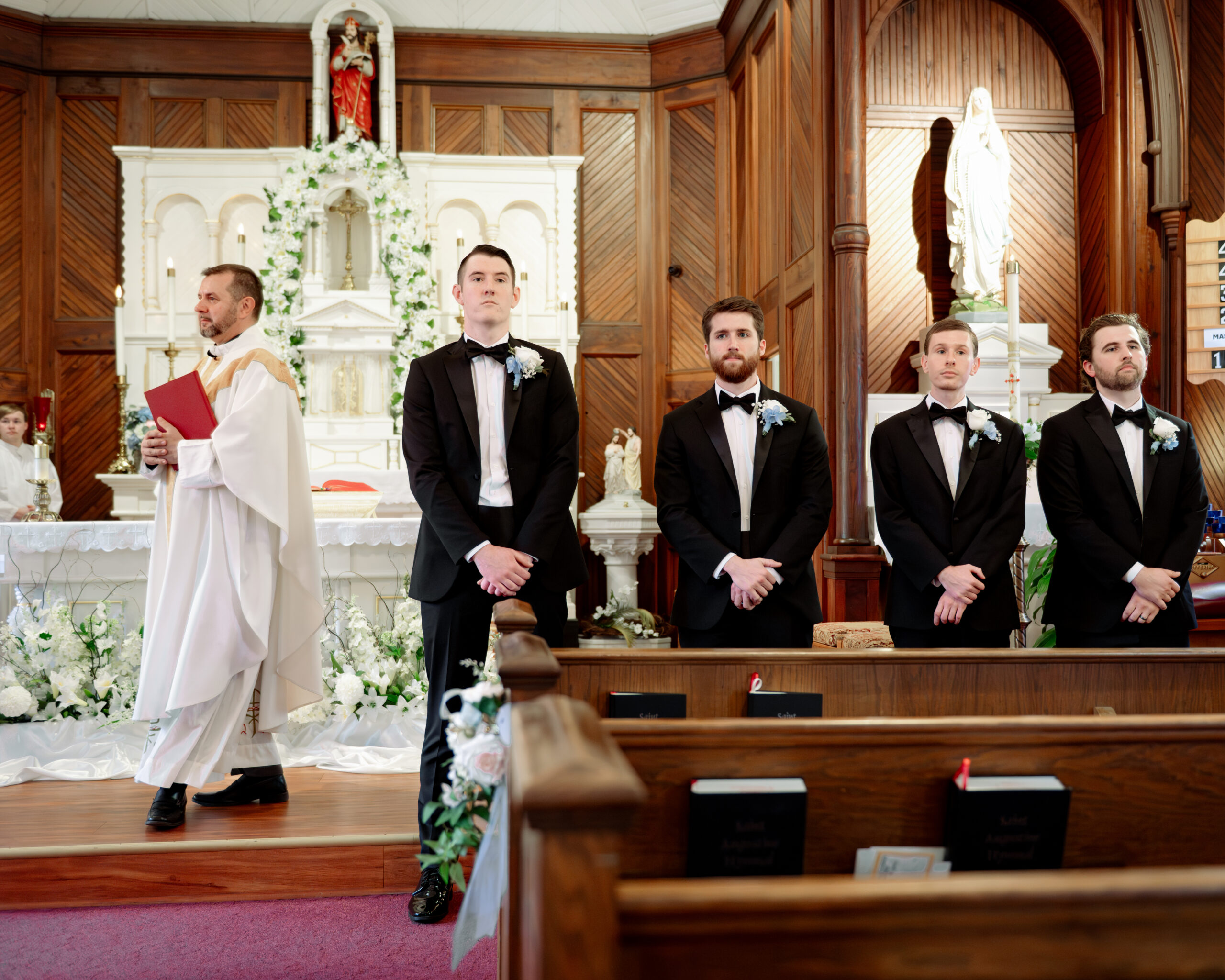 The groom stands at the altar of a tiny rural catholic parish in st. augustine florida as he waits for his bride to comedown the aisle