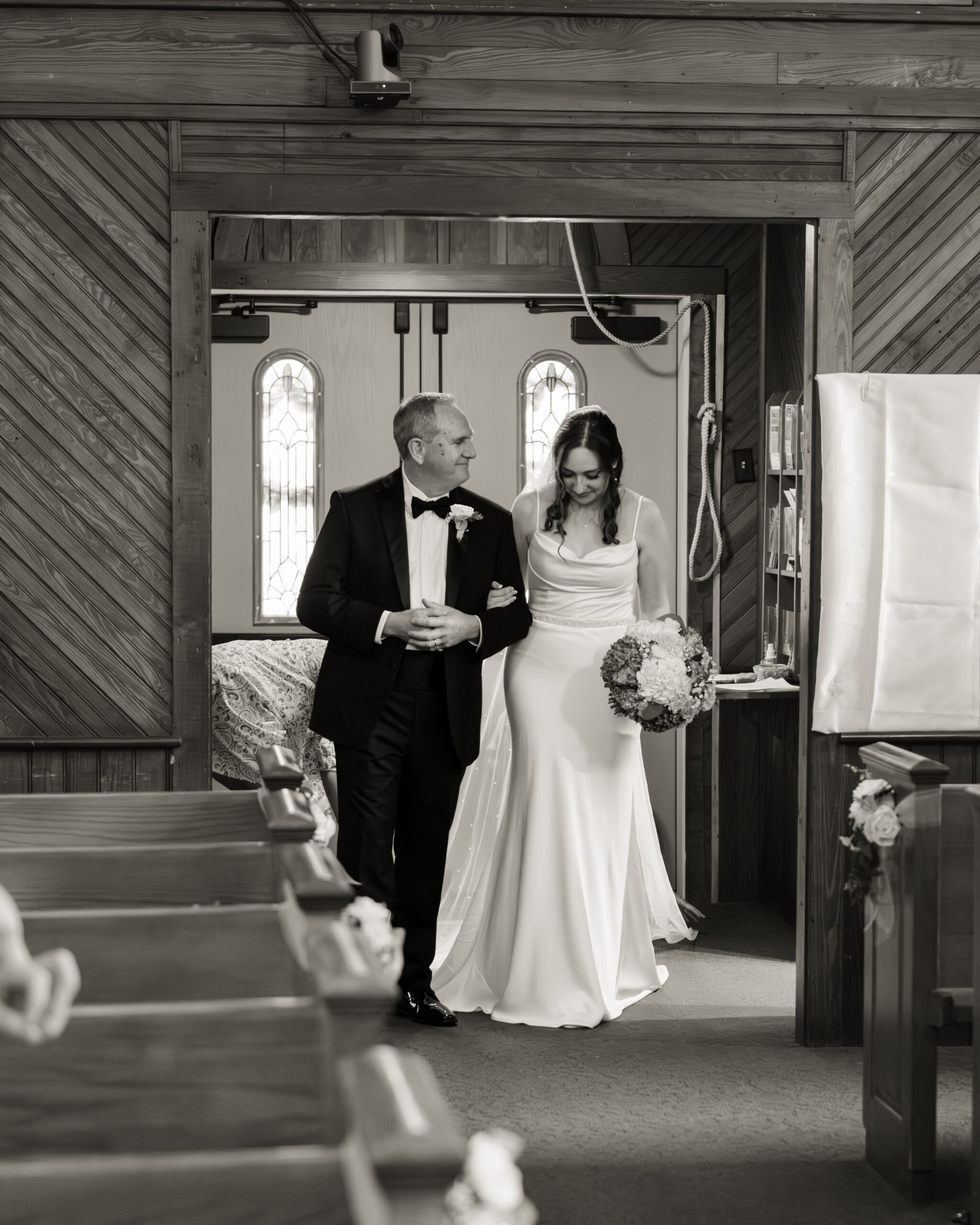A catholic bride and her father walk down the aisle of st. ambrose catholic church in elkton, florida during a catholic wedding mass