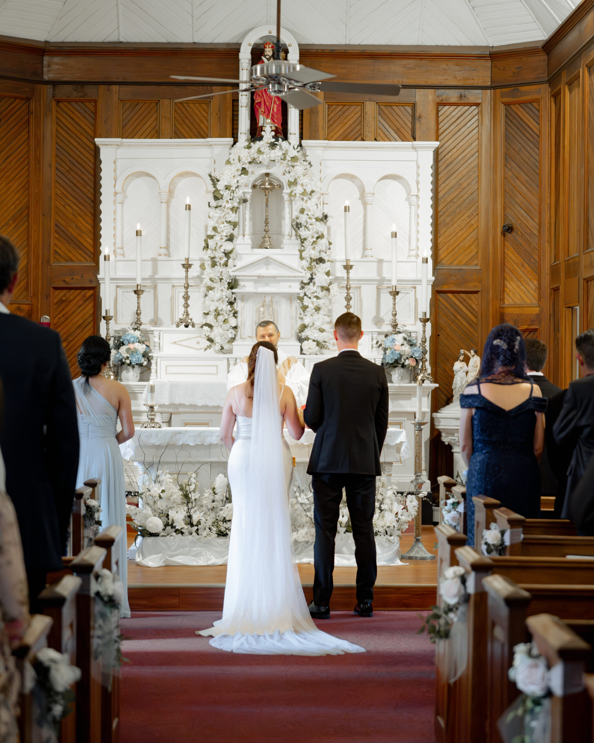 a catholic bride and groom stand at the altar of st. ambrose Catholic church in st. augustine florida during their catholic wedding Mass