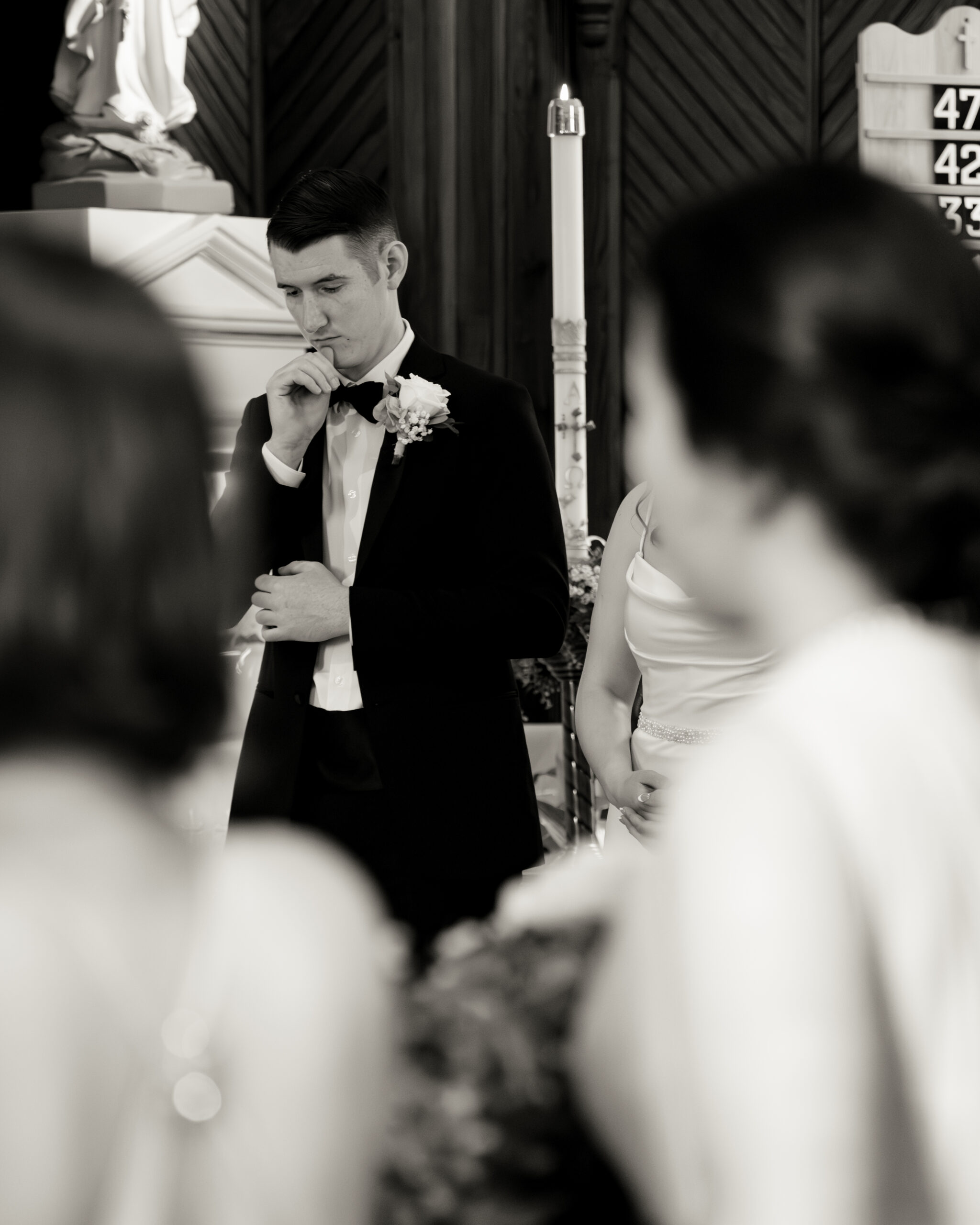a catholic groom crosses himself during his wedding Mass at st. ambrose Catholic church in st. augustine florida