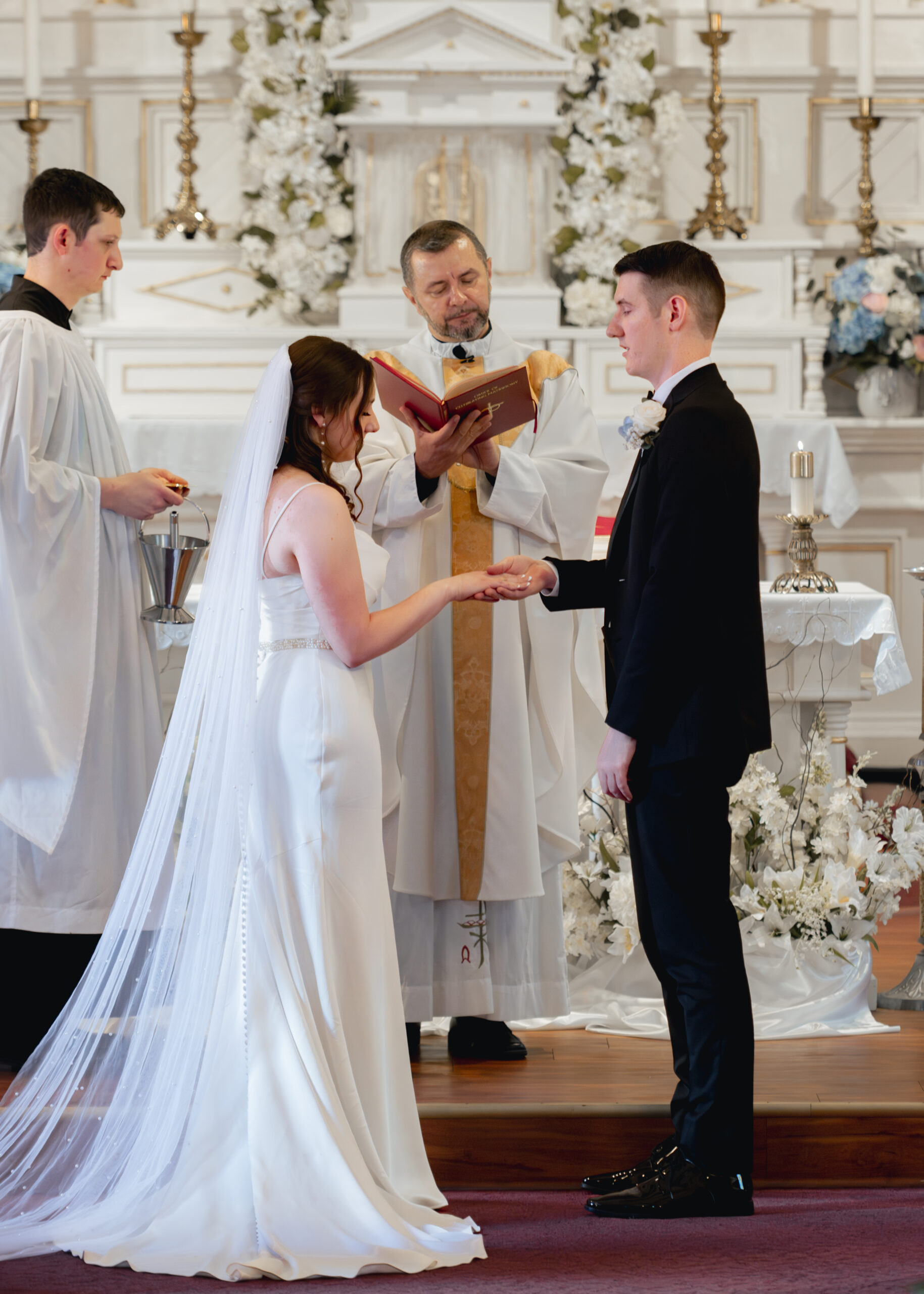 a catholic bride and groom exchange rings during their catholic wedding Mass at st. ambrose Catholic church in st. augustine florida