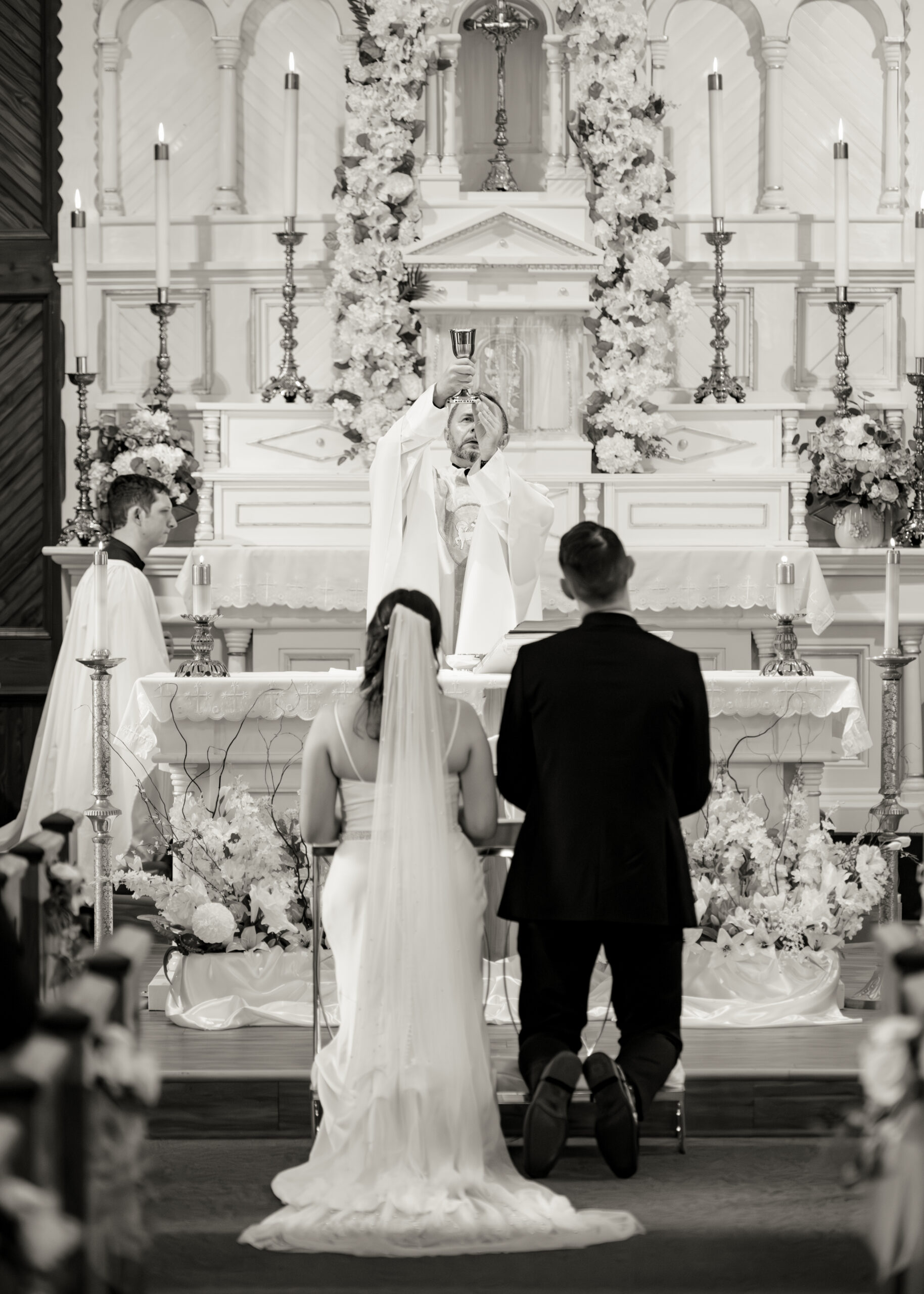 A catholic bride and groom pray during the consecration during their catholic wedding mass at st. ambrose Catholic church in st. augustine florida